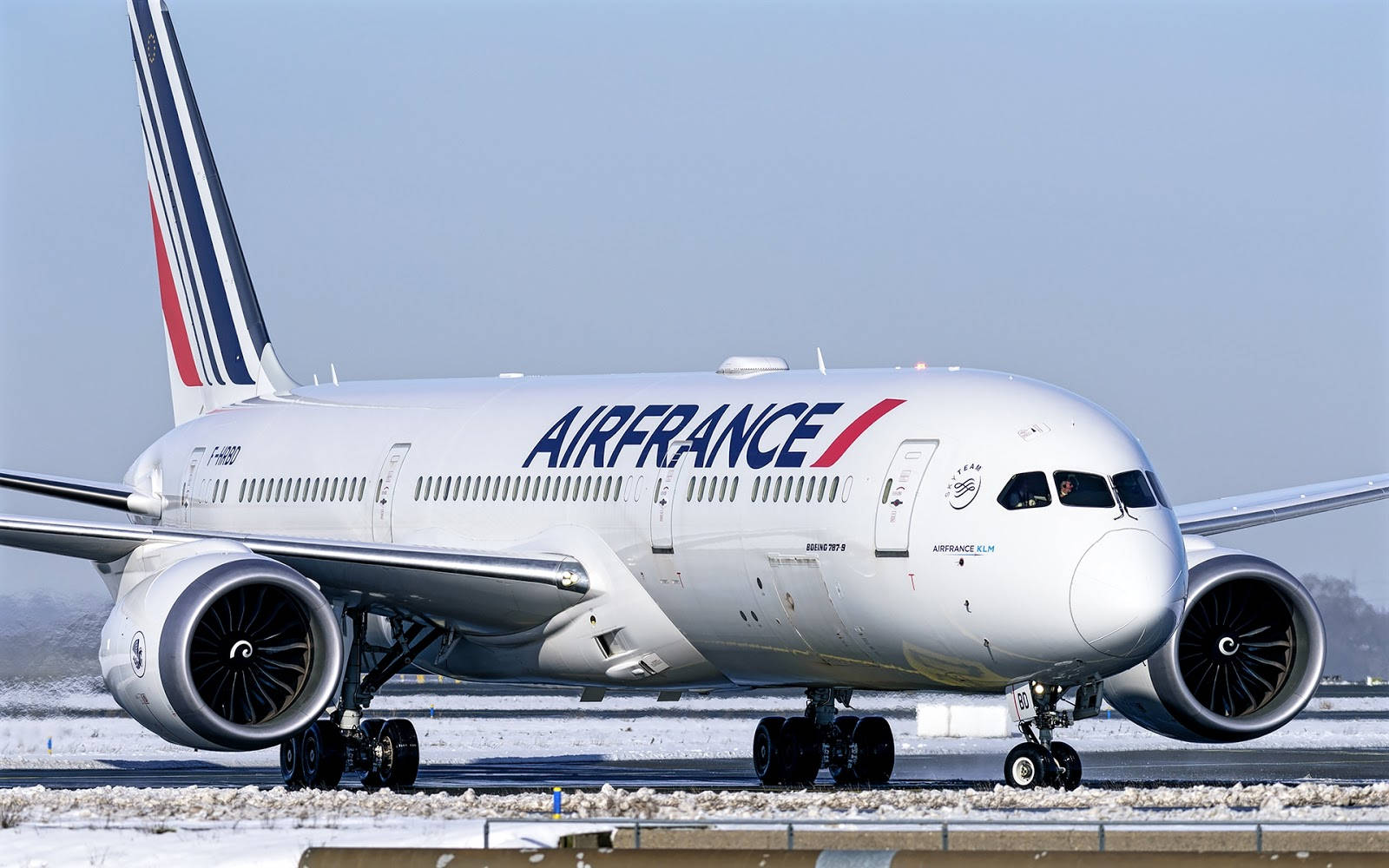Plane 桌布 壁紙 — 一架白色的法國航空波音787夢幻客機停在白雪覆蓋的跑道上，天空是淡藍色。