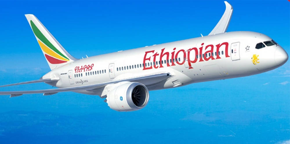  壁紙 — 一架白色的衣索比亞航空波音787夢想客機在遠方海洋地平線之上的清澈藍天中翱翔。