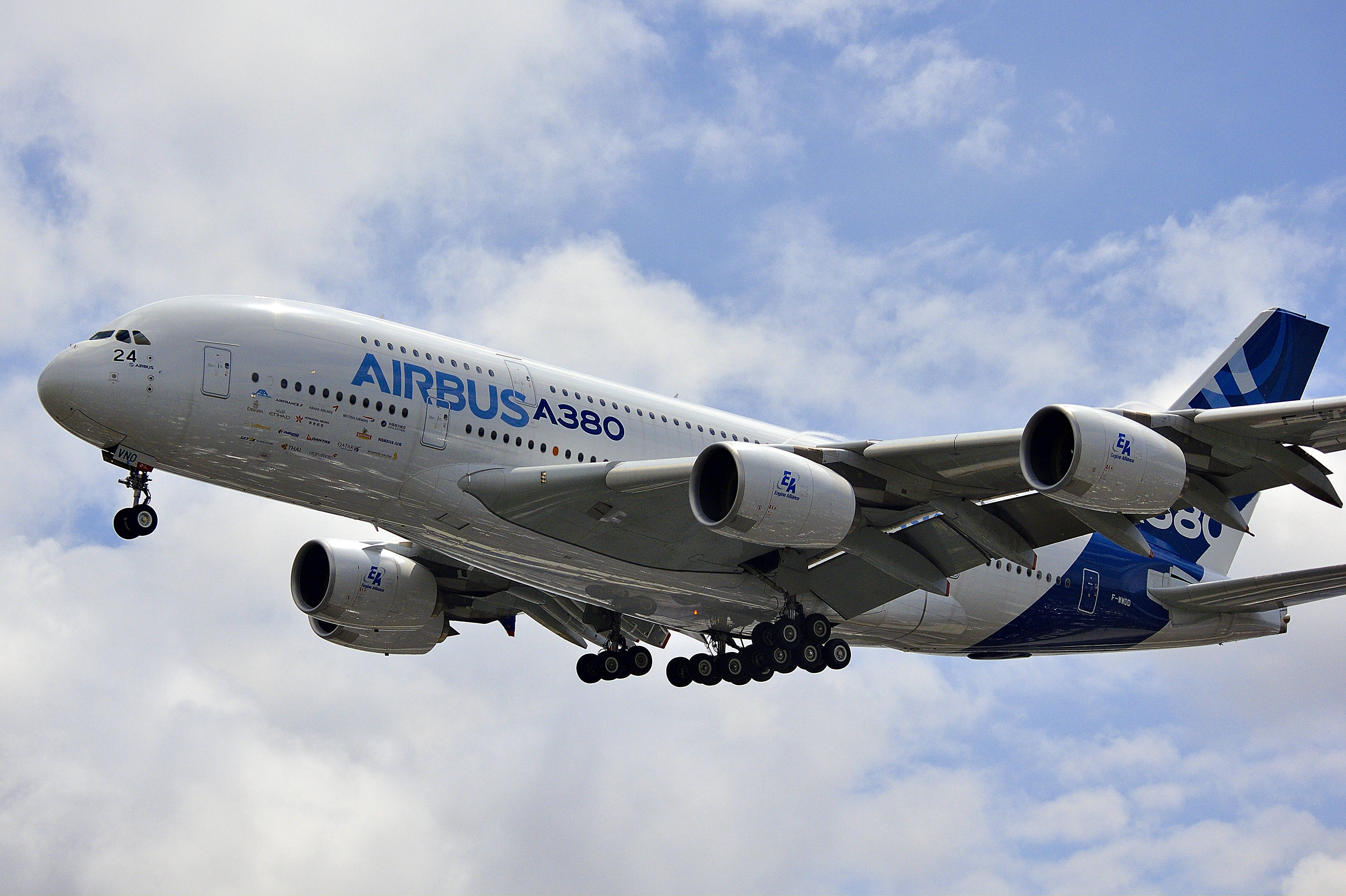 Aerospace 桌布 壁紙 — 一架白色空中巴士A380客機帶有藍色點綴，在佈滿蓬鬆白雲的明亮藍天中低飛。