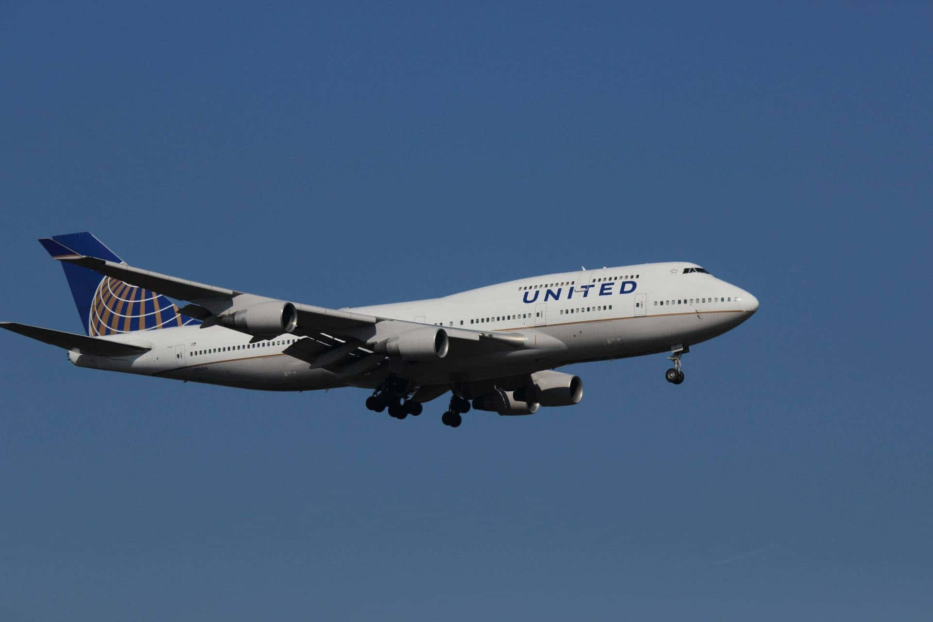 Flight 桌布 壁紙 — 一架白色聯合航空波音747，起落架放下，在清澈的藍天中翱翔。