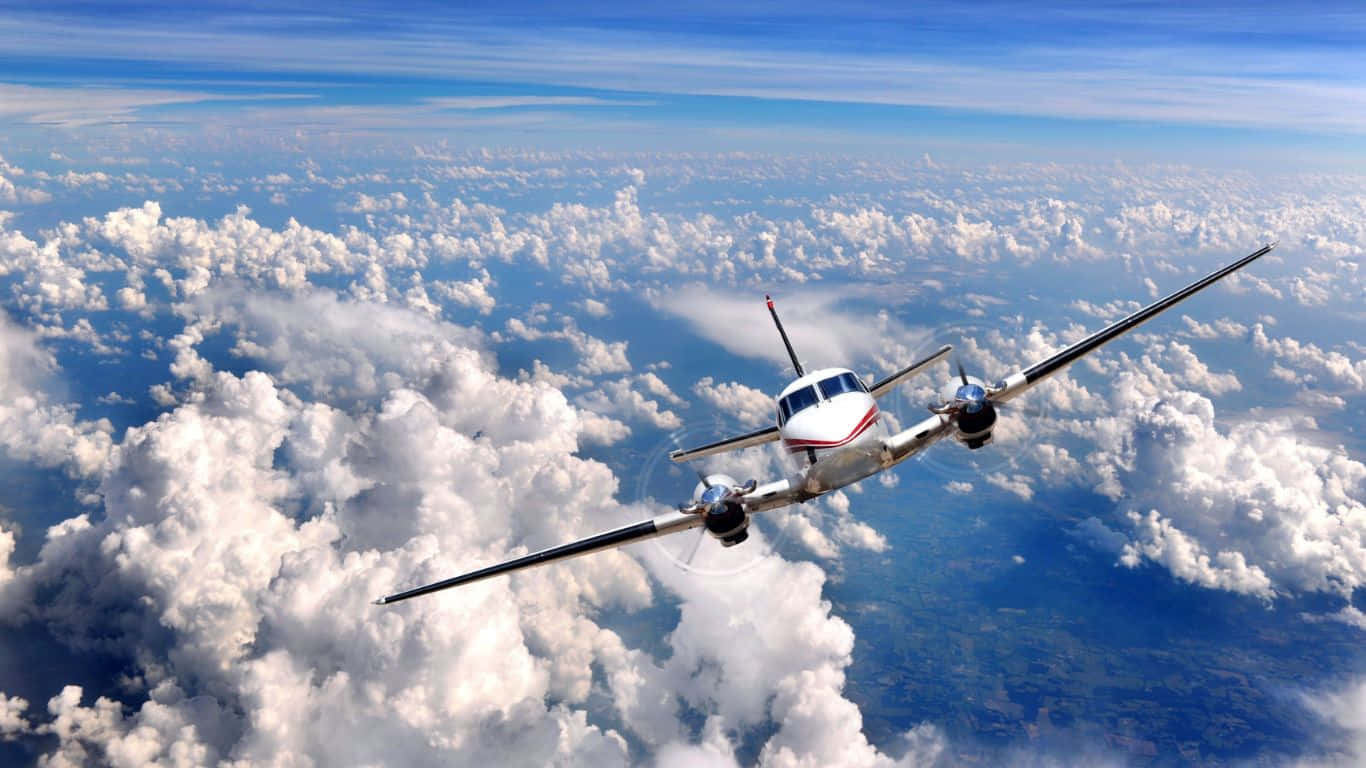 flying 桌布 壁紙 — 一架白色雙引擎螺旋槳飛機在晴朗的藍天下翱翔於蓬鬆的白雲之上。