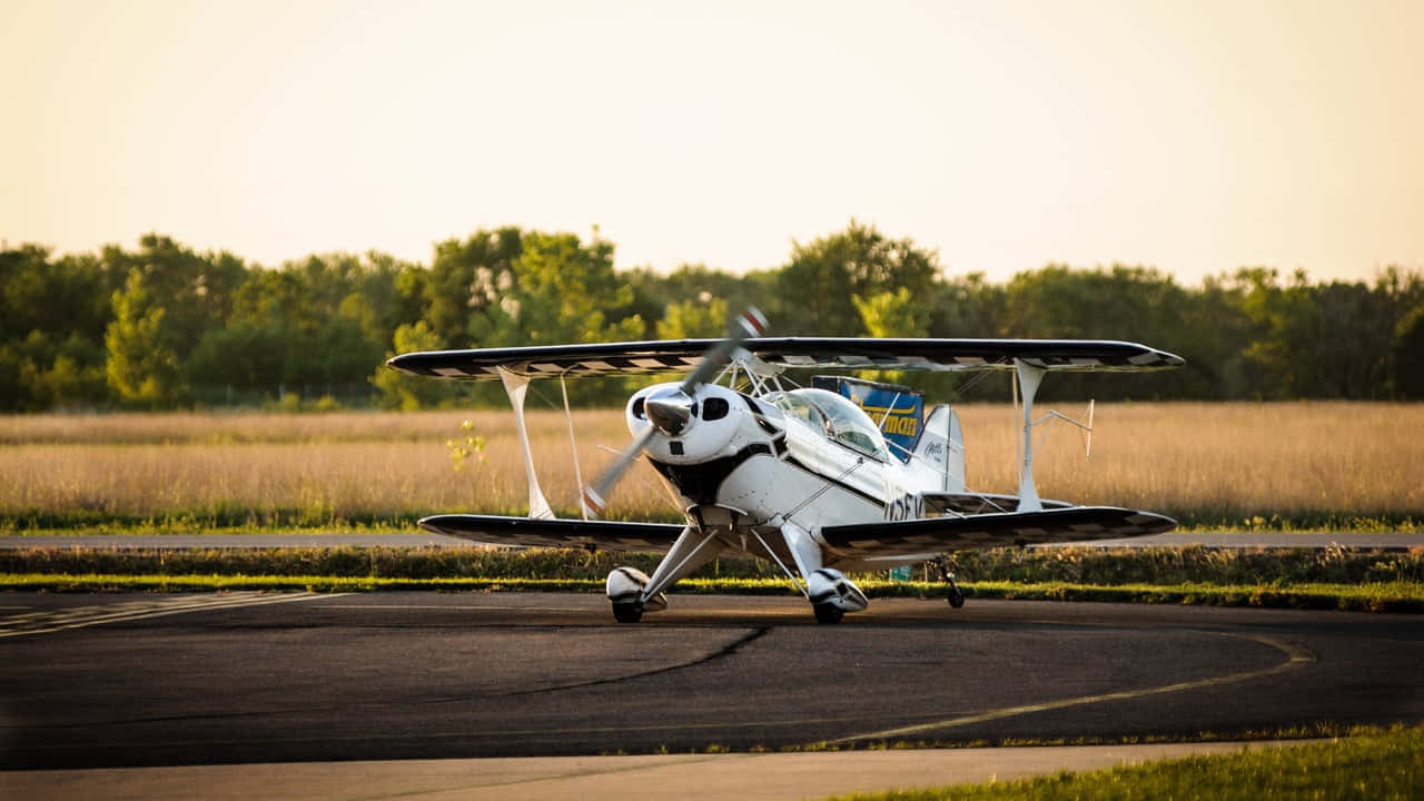 Aircraft 桌布 壁紙 — 一架白色雙翼飛機停在跑道上，夕陽的金色光芒在停機坪和草地上投下長長的影子。
