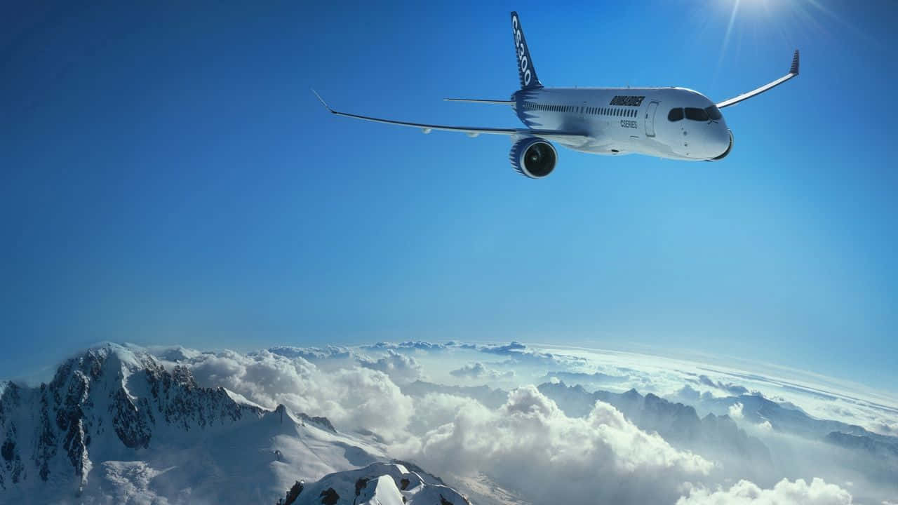 720p Plane 桌布 壁紙 — 一架白色飛機在晴朗藍天和陽光下，翱翔於積雪山脈和蓬鬆雲層之上。