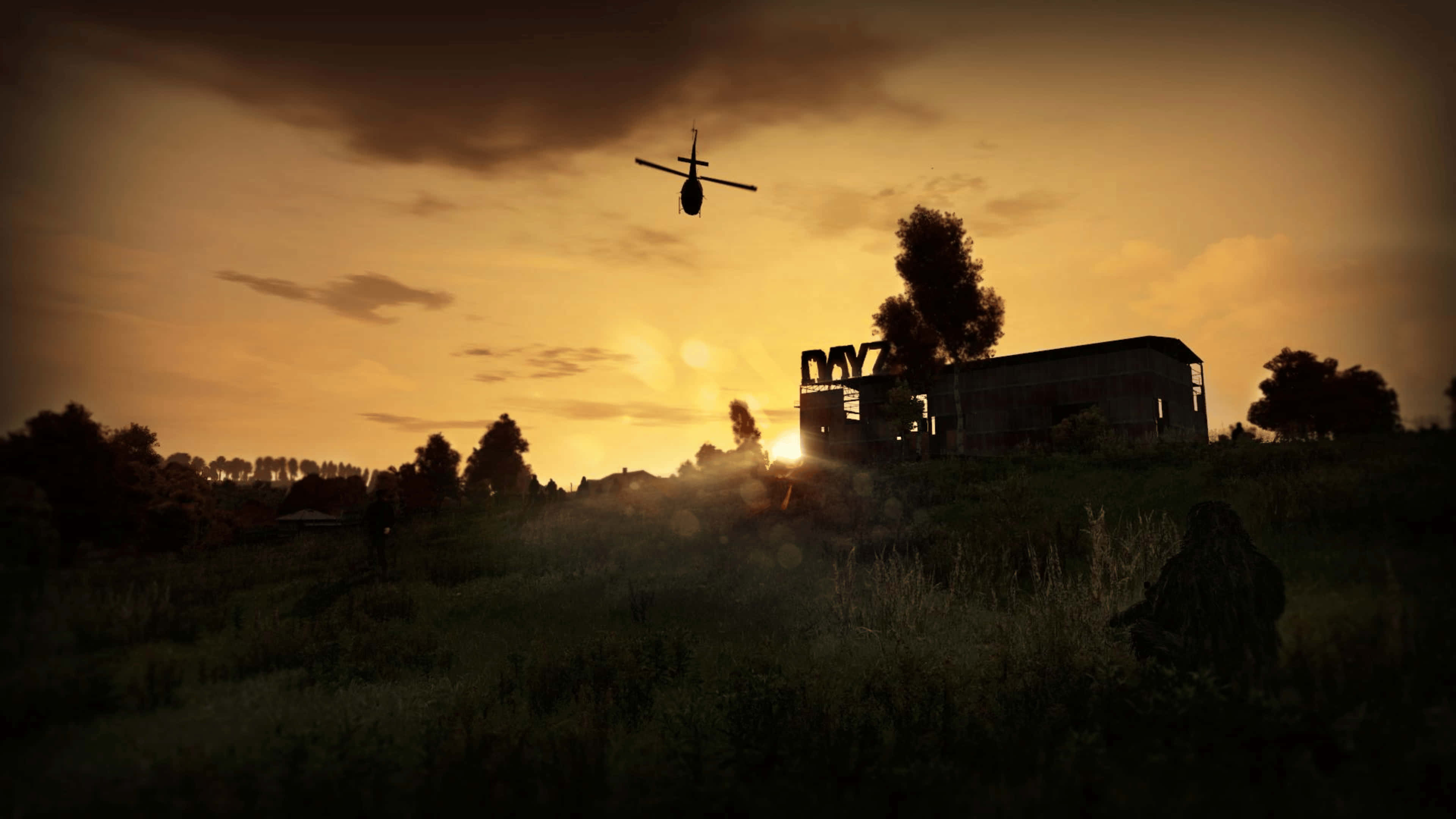 game 桌布 壁紙 — 一架直升機在金色夕陽的映襯下形成剪影，飛過草地上一座廢墟建築。