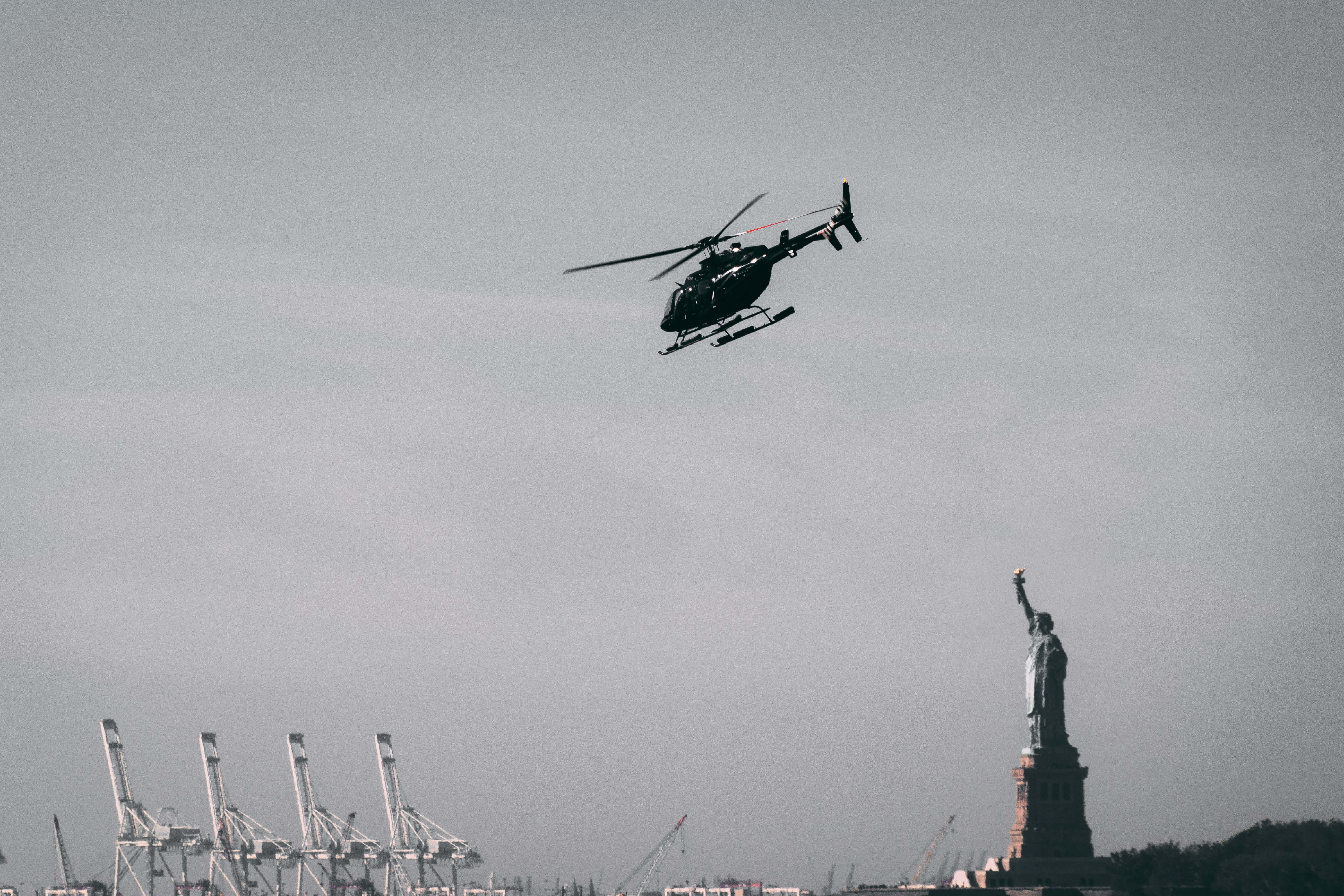 Helicopter 桌布 壁紙 — 一架直升機飛過自由女神像，背景是朦朧的天空和港口起重機。