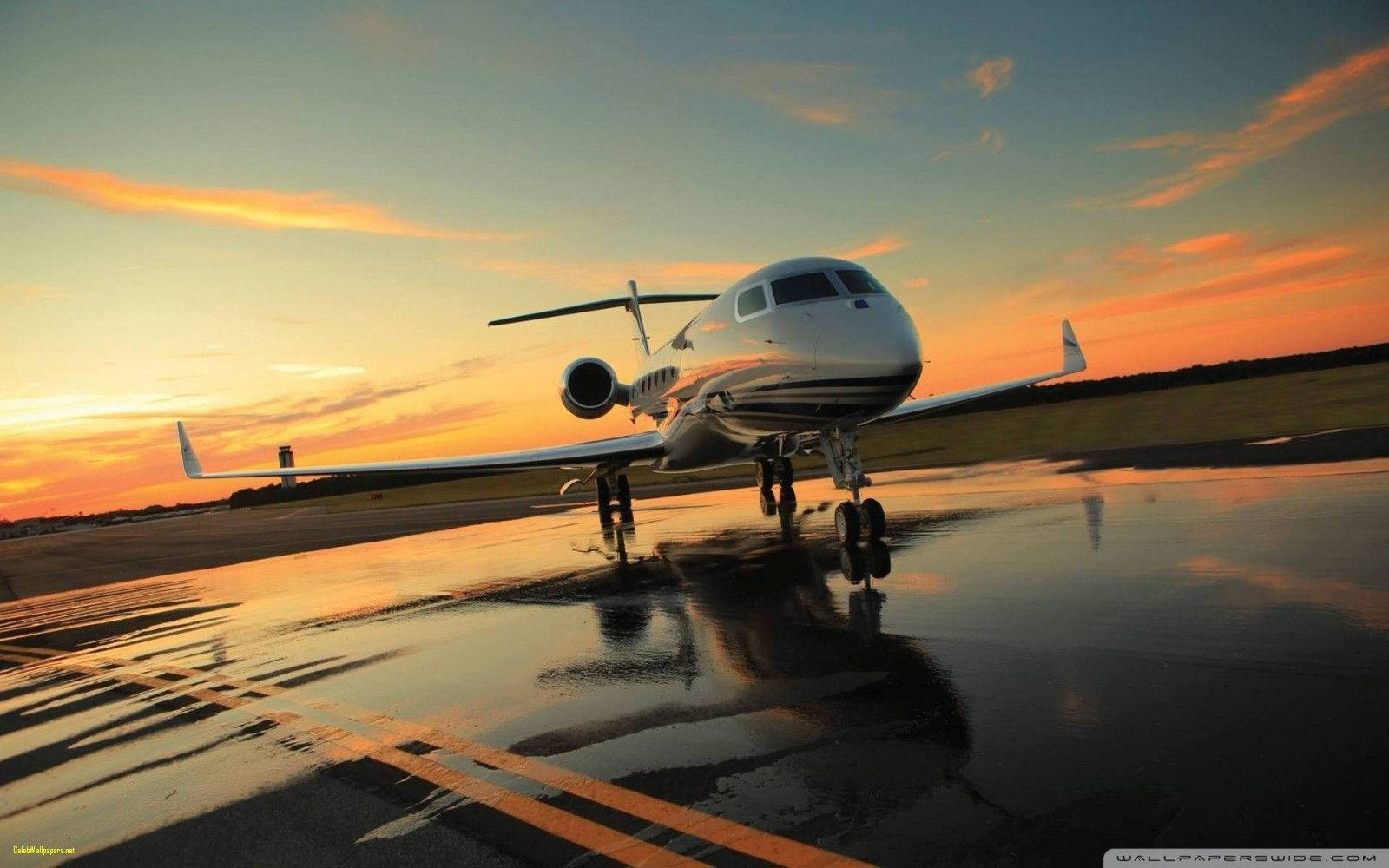 4K 飛機壁紙 桌布 壁紙 — 一架私人飛機停在濕滑的跑道上，反射出充滿活力的橙色和藍色日落天空。