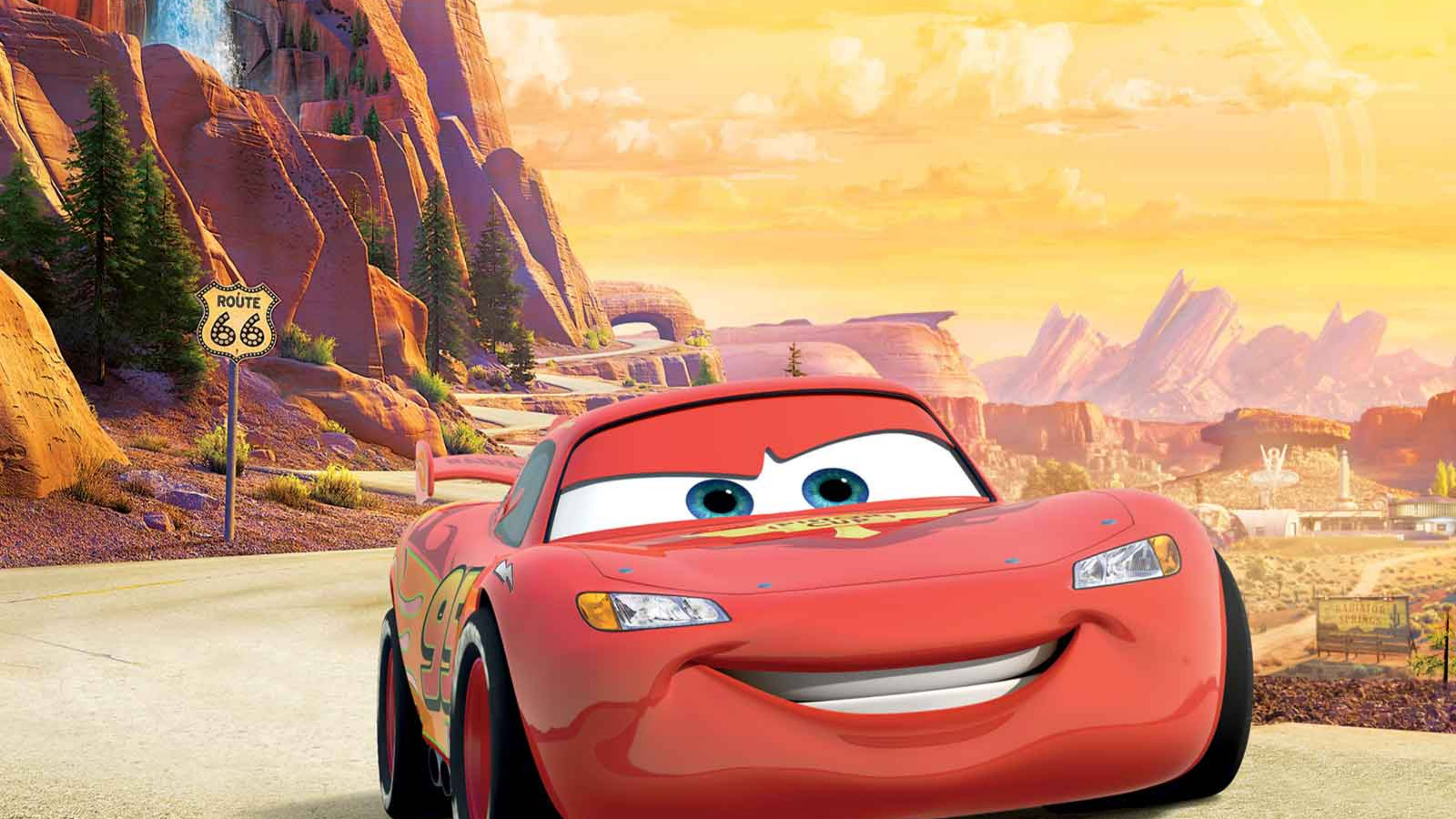 Pixar 桌布 壁紙 — 一架笑容燦爛的紅色賽車在金色夕陽天空下行駛在沙漠公路上。