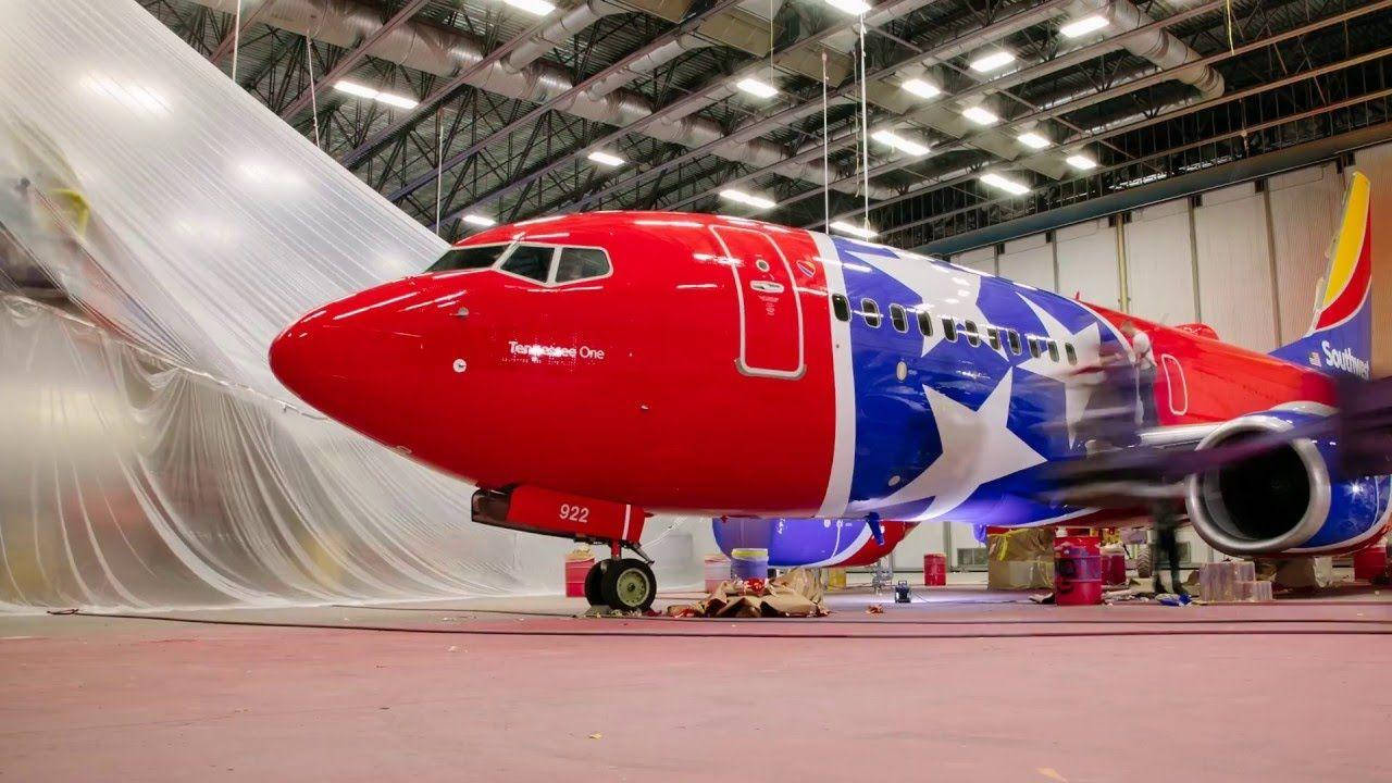 Plane 桌布 壁紙 — 一架紅、藍、白星條紋的西南航空飛機停在機庫內，附近掛有塑膠布。
