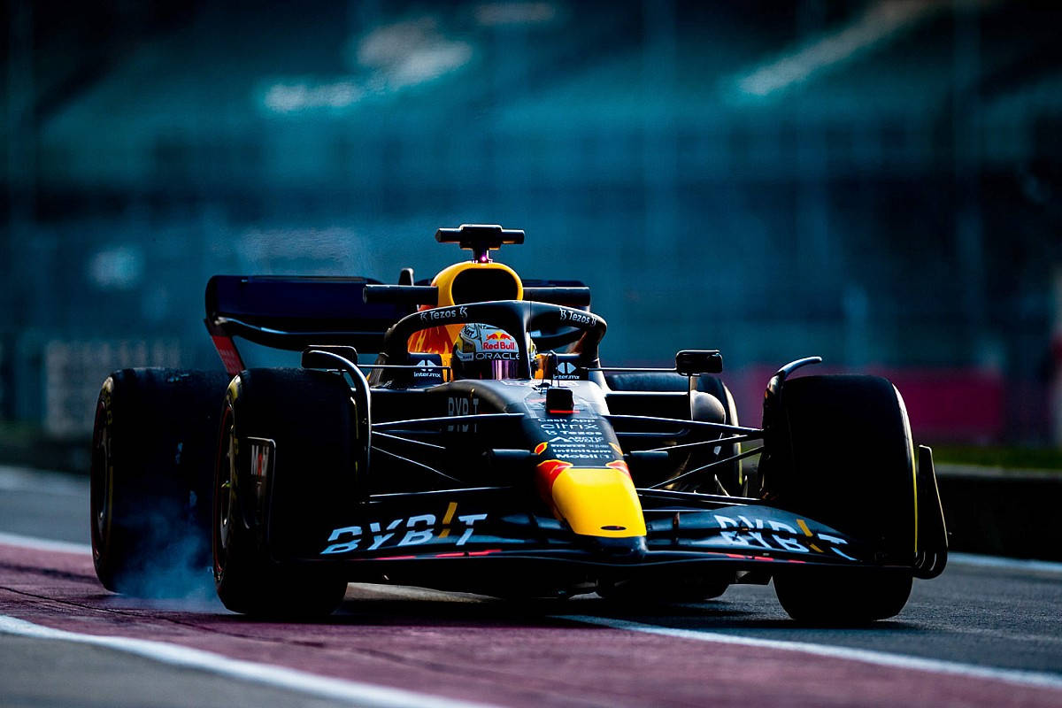 Red Bull 桌布 壁紙 — 一架紅牛一級方程式賽車，車手戴著頭盔，在戲劇性的藍色燈光下於賽道上疾馳，輪胎冒出煙霧。