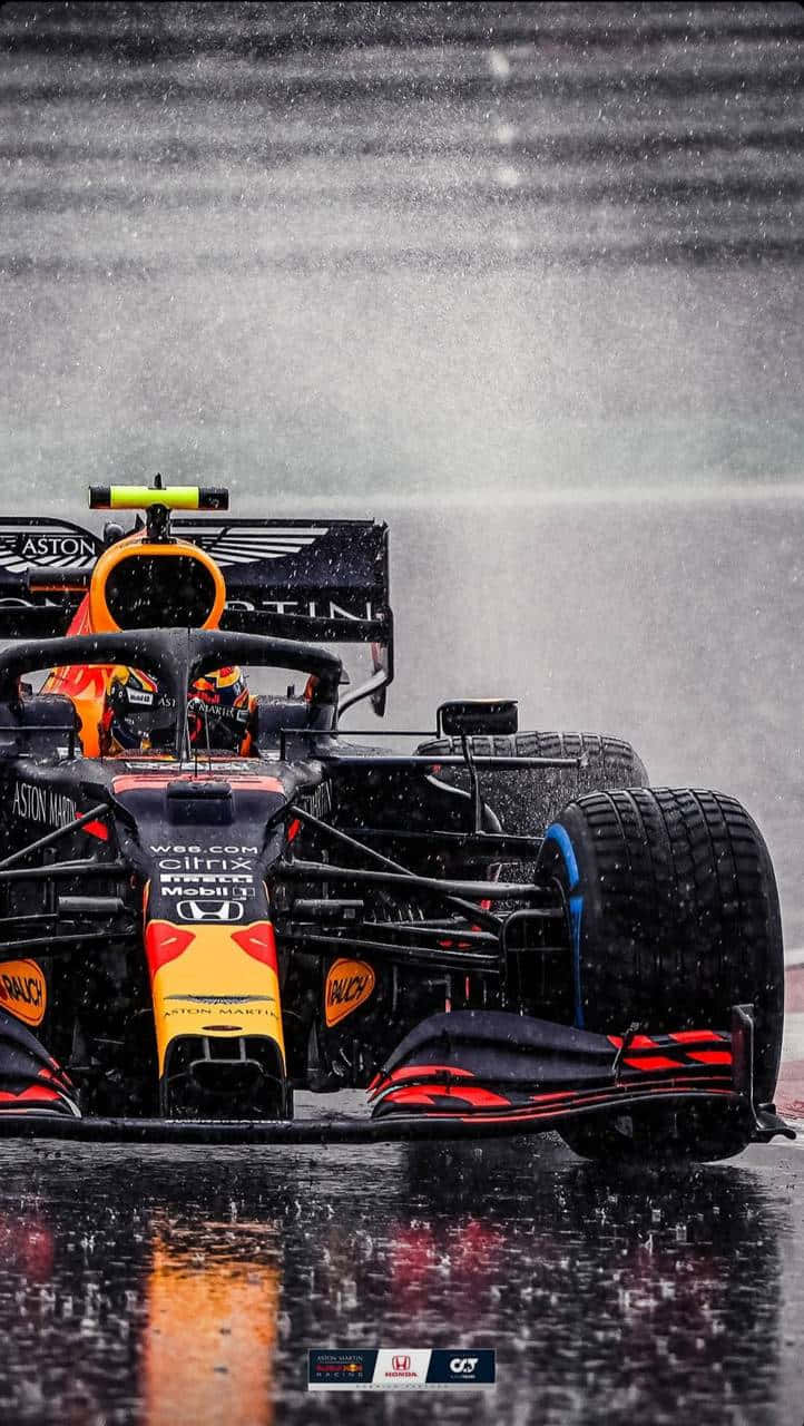 Formula One 桌布 壁紙 — 一架紅牛車隊一級方程式賽車在滂沱大雨中於濕滑賽道上疾馳，輪胎濺起水花。
