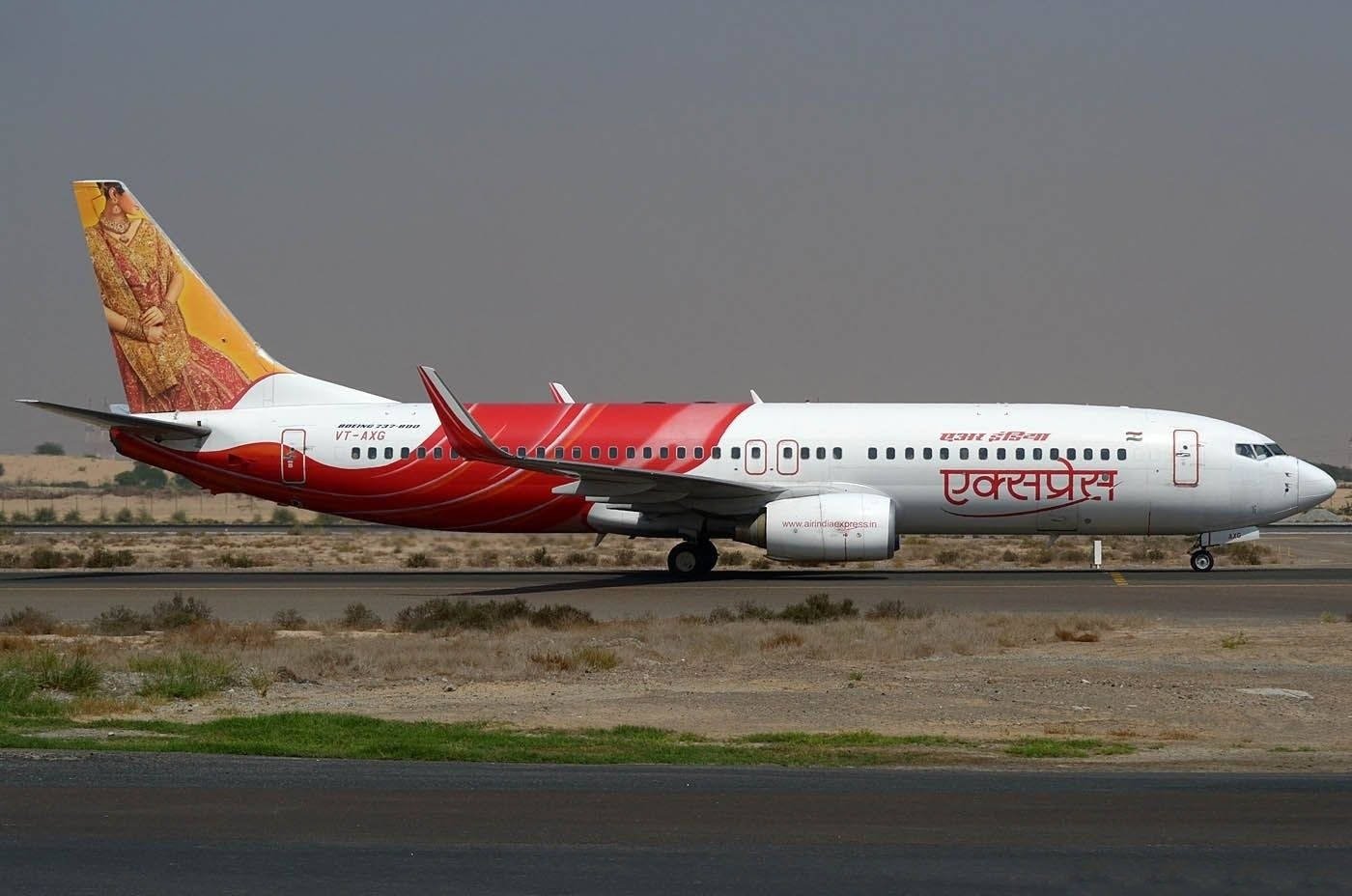 飛機 桌布 壁紙 — 一架紅白塗裝的印度航空快運波音737在朦朧沙漠背景下於跑道上滑行。