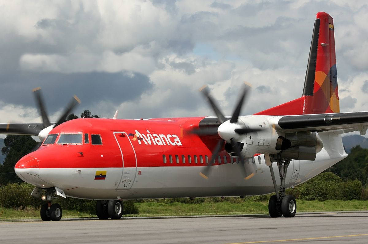  壁紙 — 一架紅白相間的 Avianca 渦輪螺旋槳飛機停在停機坪上，背景是陰天和綠樹。