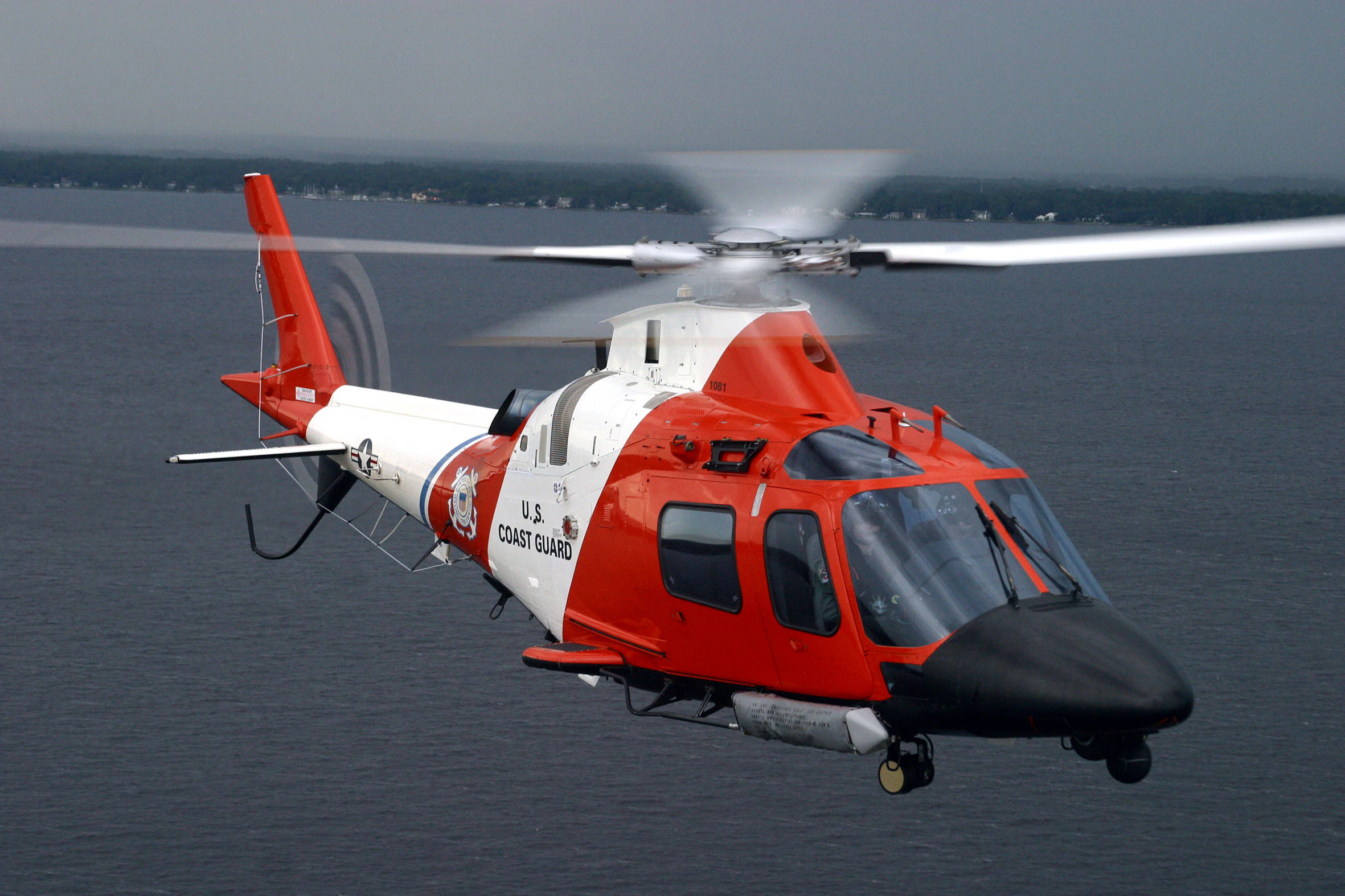 helicopter 4K 桌布 壁紙 — 一架紅白相間的美國海岸警衛隊直升機在陰天低空盤旋於漆黑的海面上。