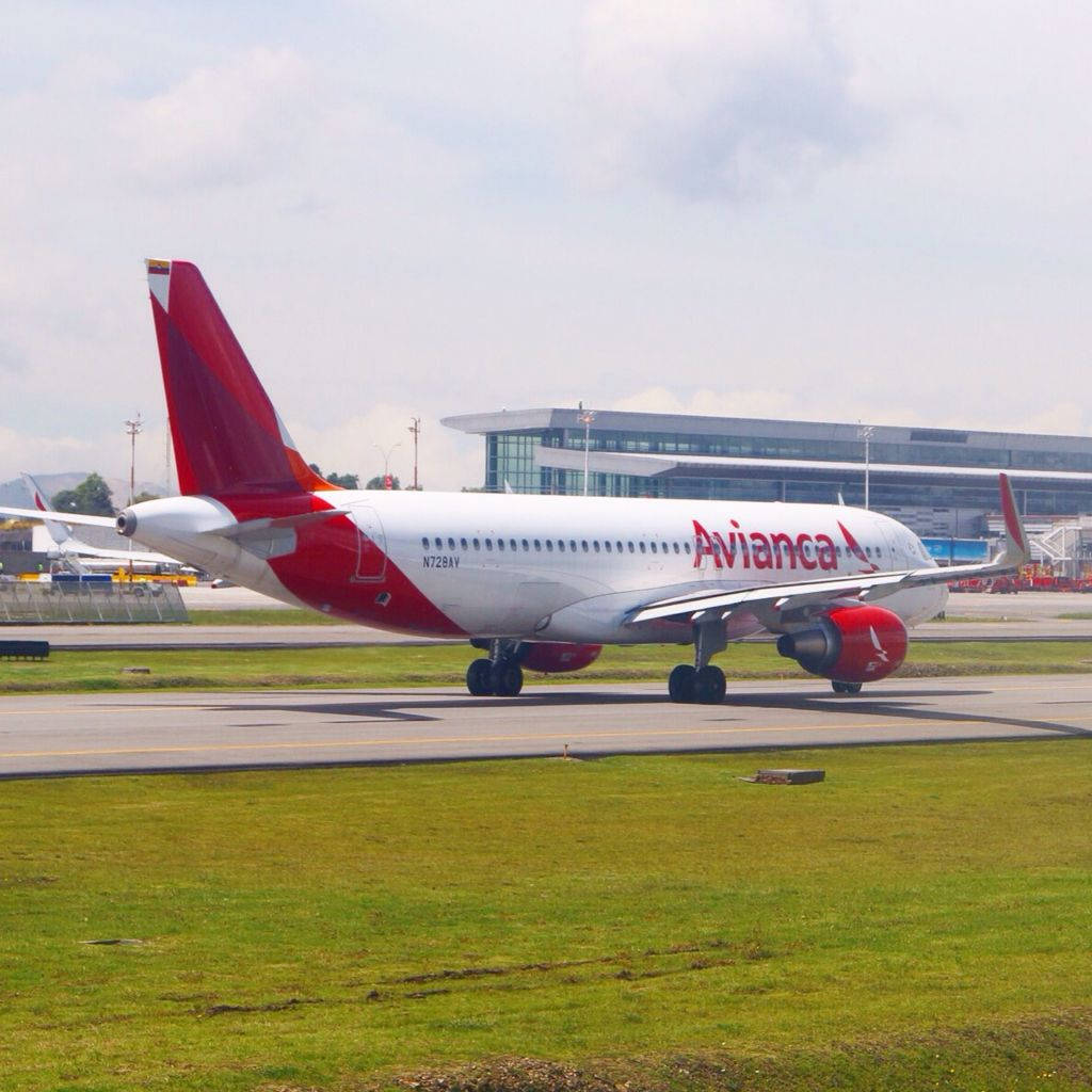 Airport 桌布 壁紙 — 一架紅色尾翼和引擎的 Avianca 客機在陰天下滑行在跑道旁，旁邊有綠色草地。