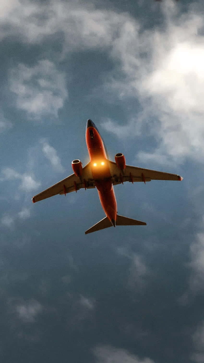 Plane 桌布 壁紙 — 一架紅色飛機在戲劇性的多雲天空中翱翔，帶有發光的導航燈。