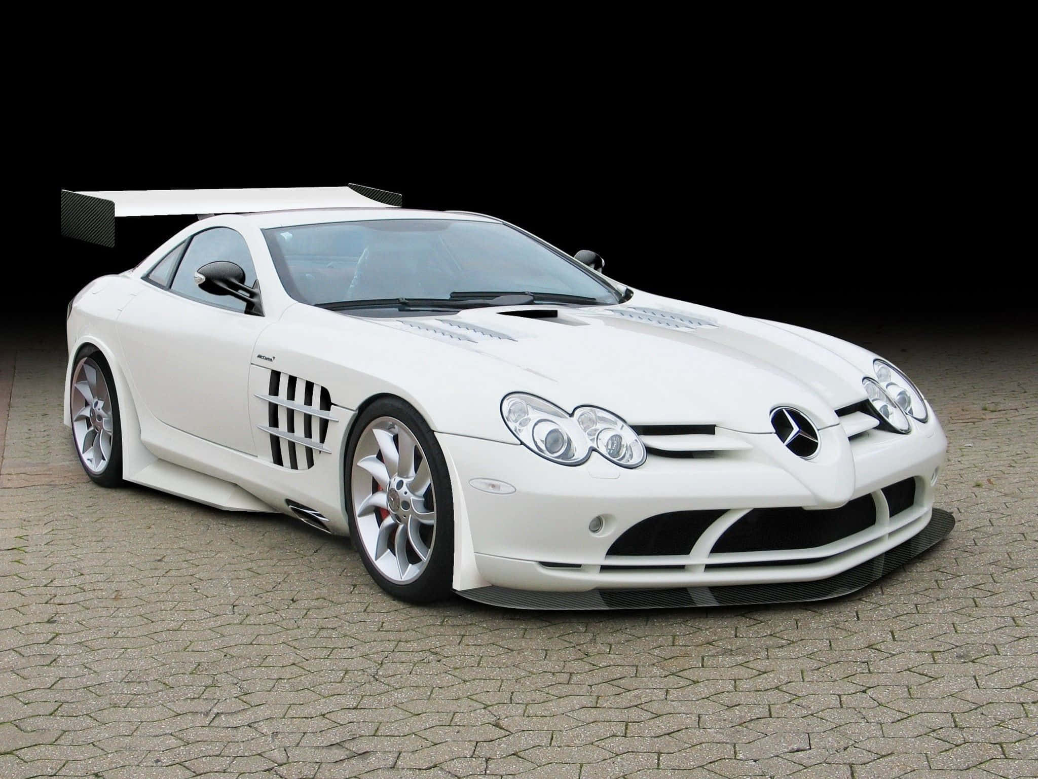 白色 桌布 壁紙 — 一架純白色的 Mercedes-Benz SLR McLaren 跑車，帶有大型尾翼，停在黑色背景的鵝卵石路面上。