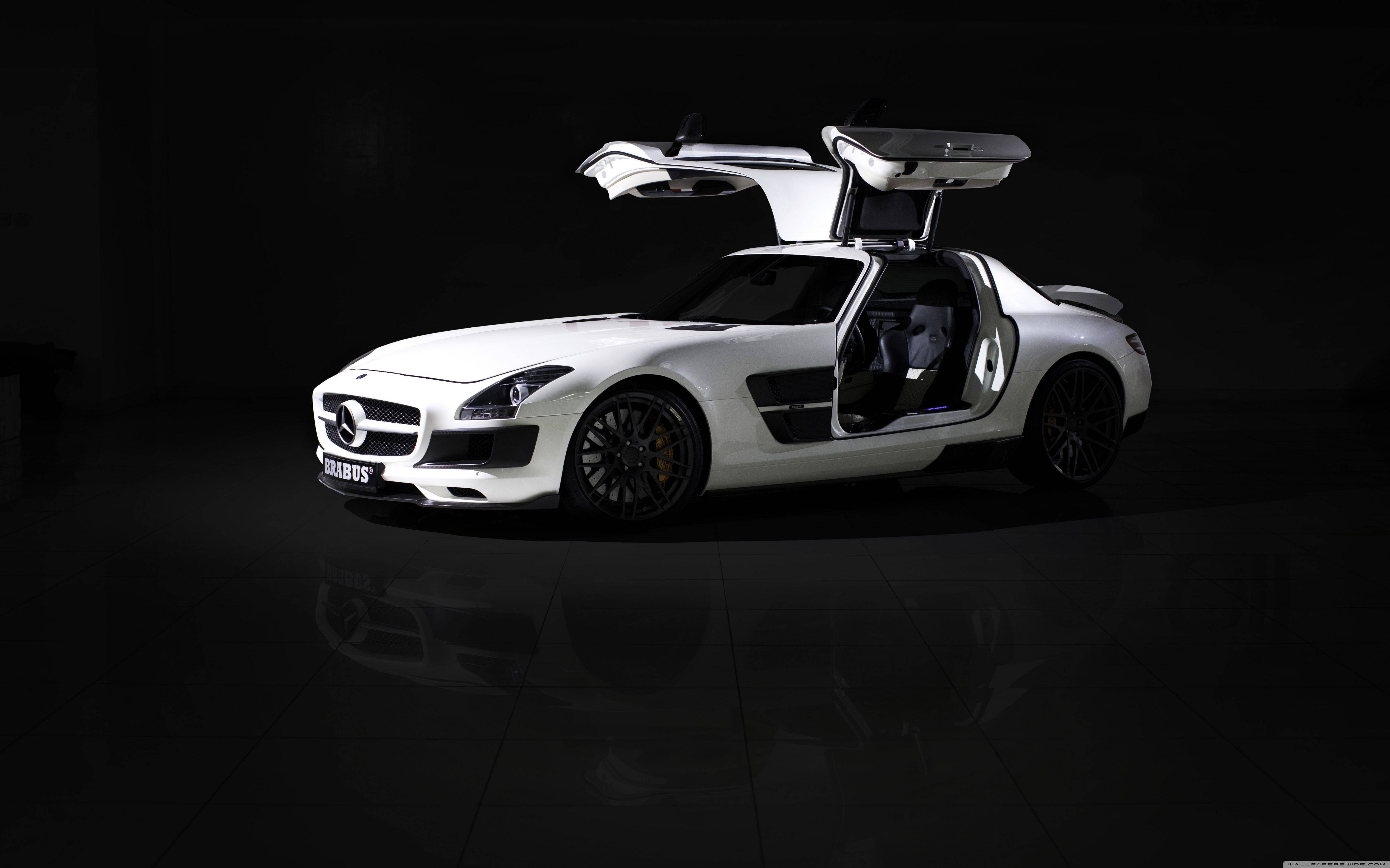 Mercedes 桌布 壁紙 — 一架純白色的賓士 SLS AMG 鷗翼門打開，在黑色攝影棚地板反射瓷磚上戲劇性地照明。