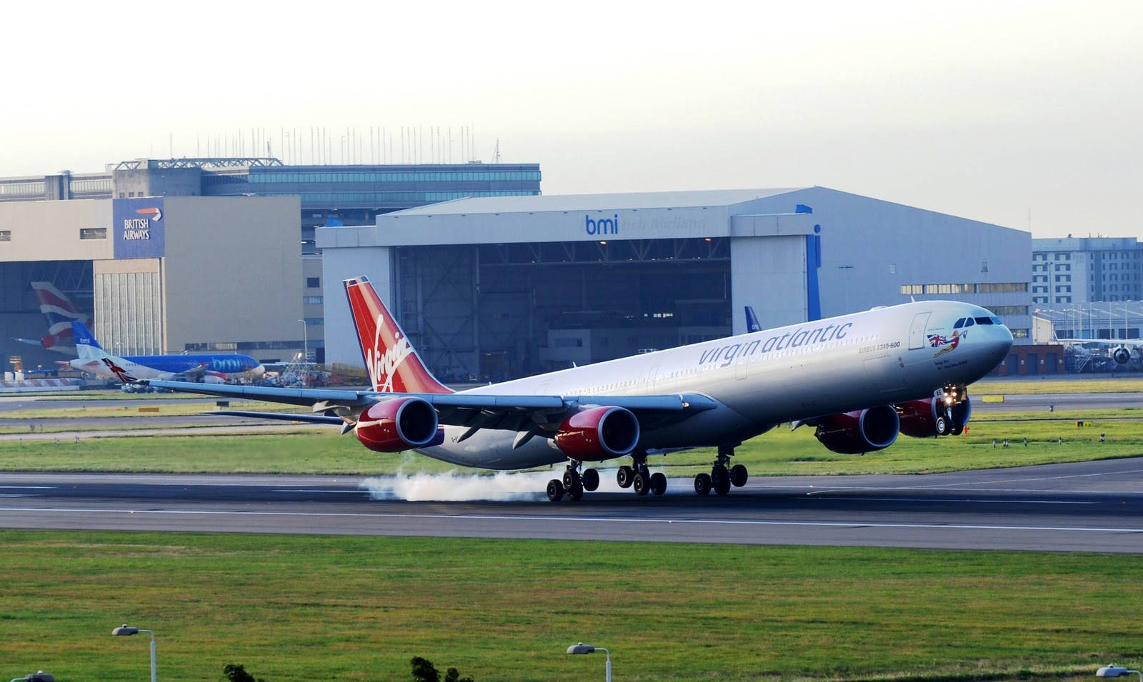 Airport 桌布 壁紙 — 一架維珍航空空中巴士A340在機場跑道上滑行，背景可見機庫和另一架飛機。