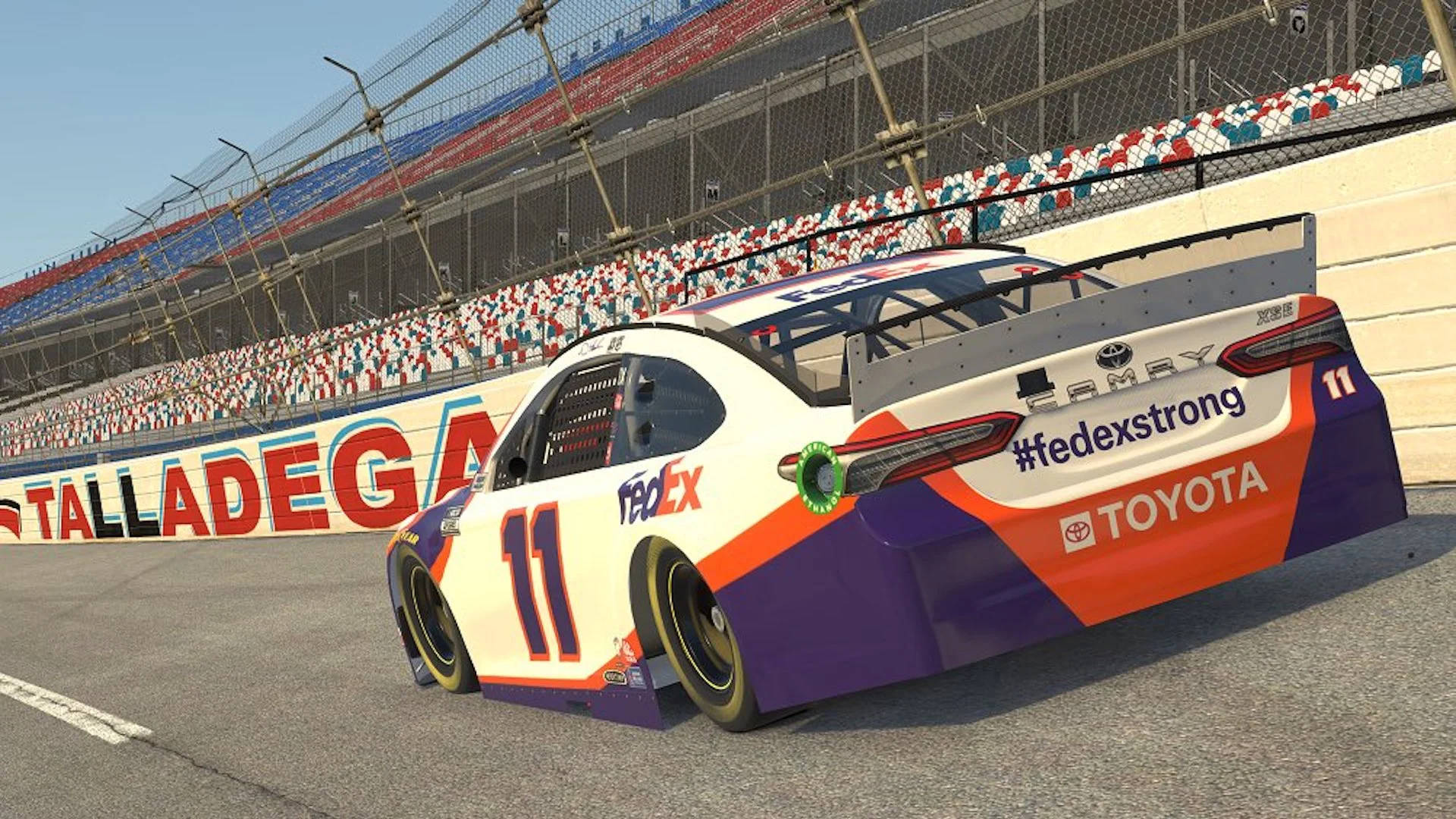 Denny Hamlin 桌布 壁紙 — 一架編號11的FedEx Toyota賽車在塔拉迪加賽道上疾馳，看台座無虛席，天空清澈湛藍。