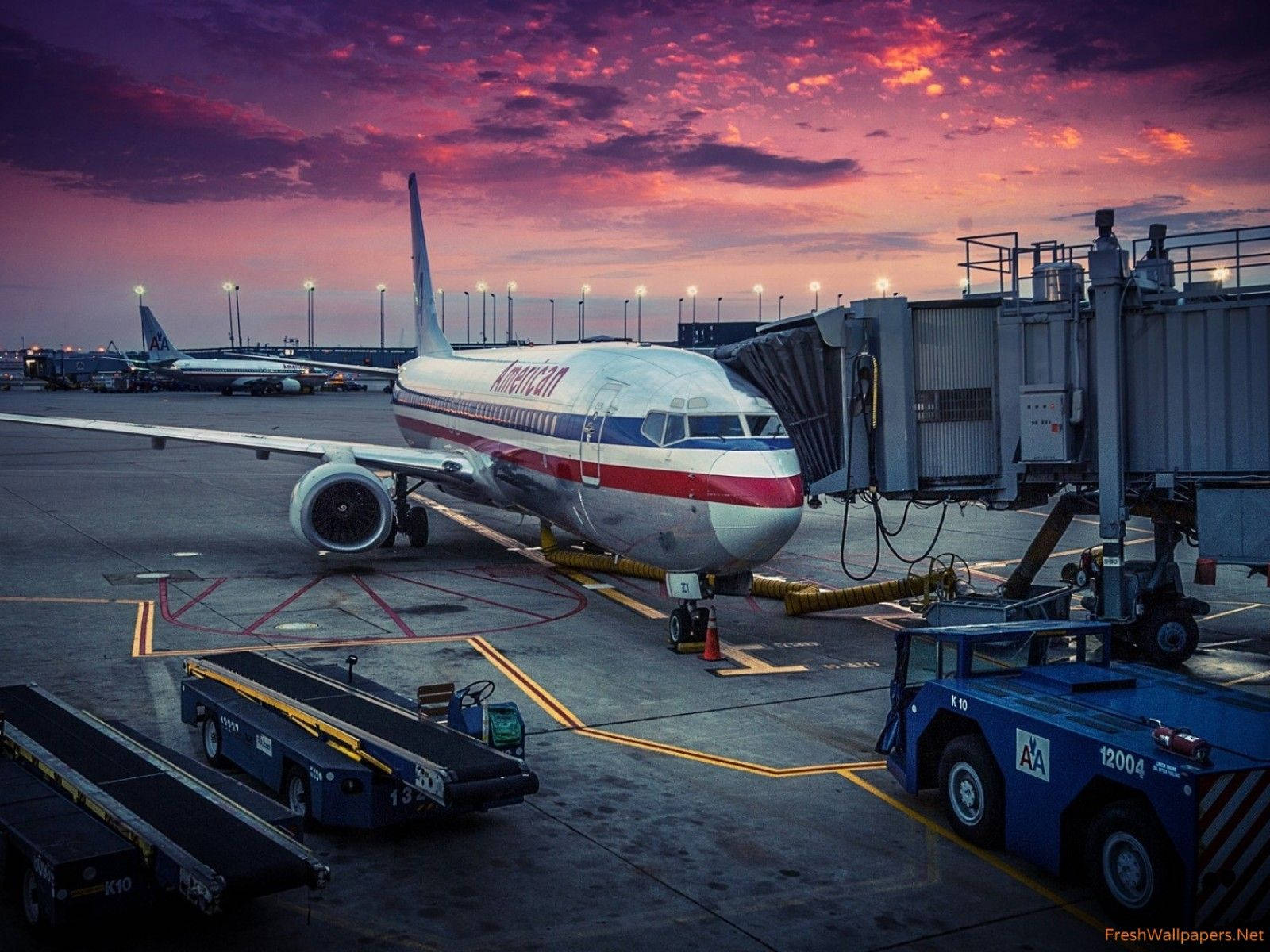 American 桌布 壁紙 — 一架美國航空噴射機停在機場閘口，背景是戲劇性的粉紅與紫色日落天空。