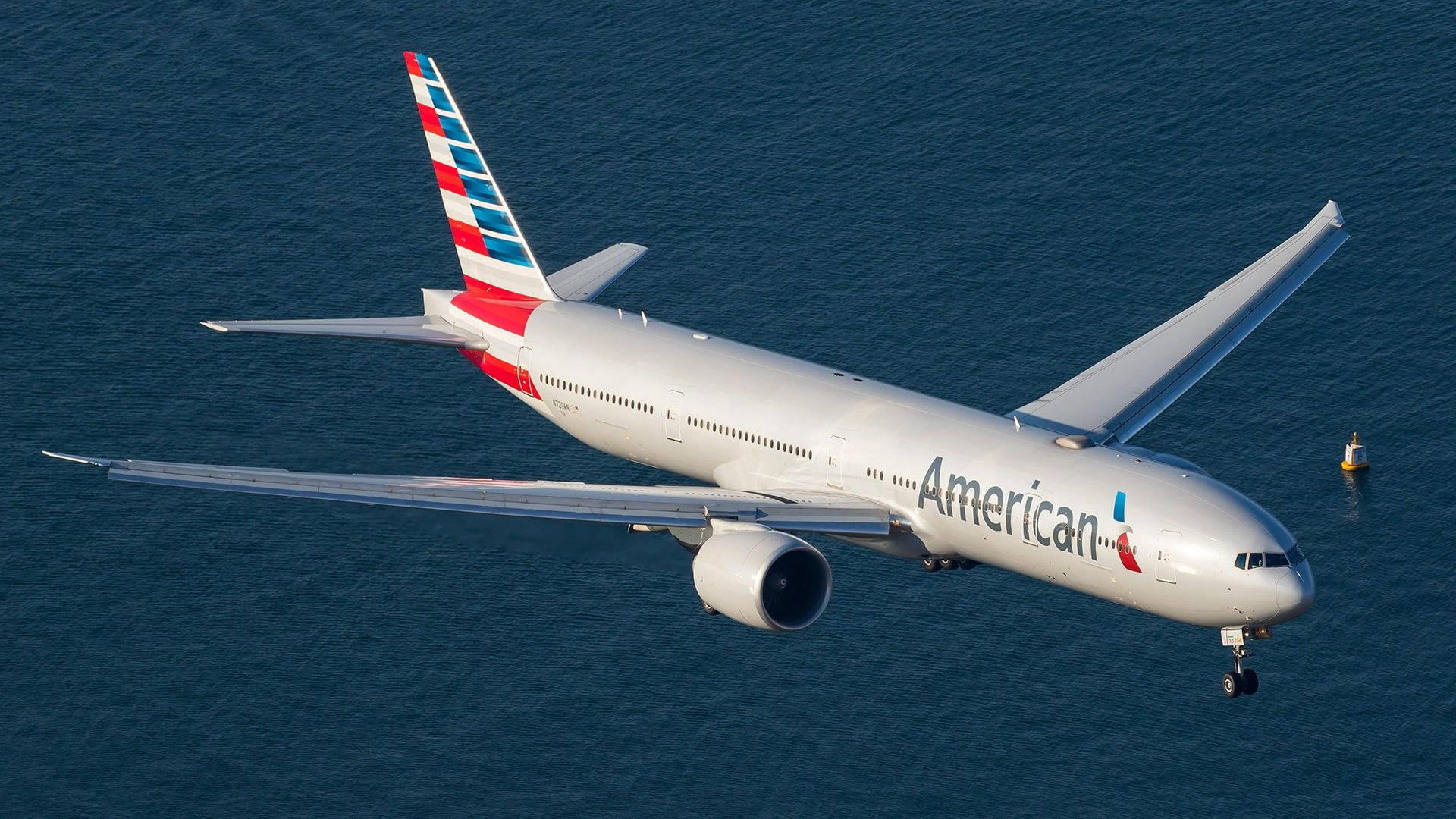 Airlines 桌布 壁紙 — 一架美國航空噴射機放下起落架，低飛過深藍色海洋水域。