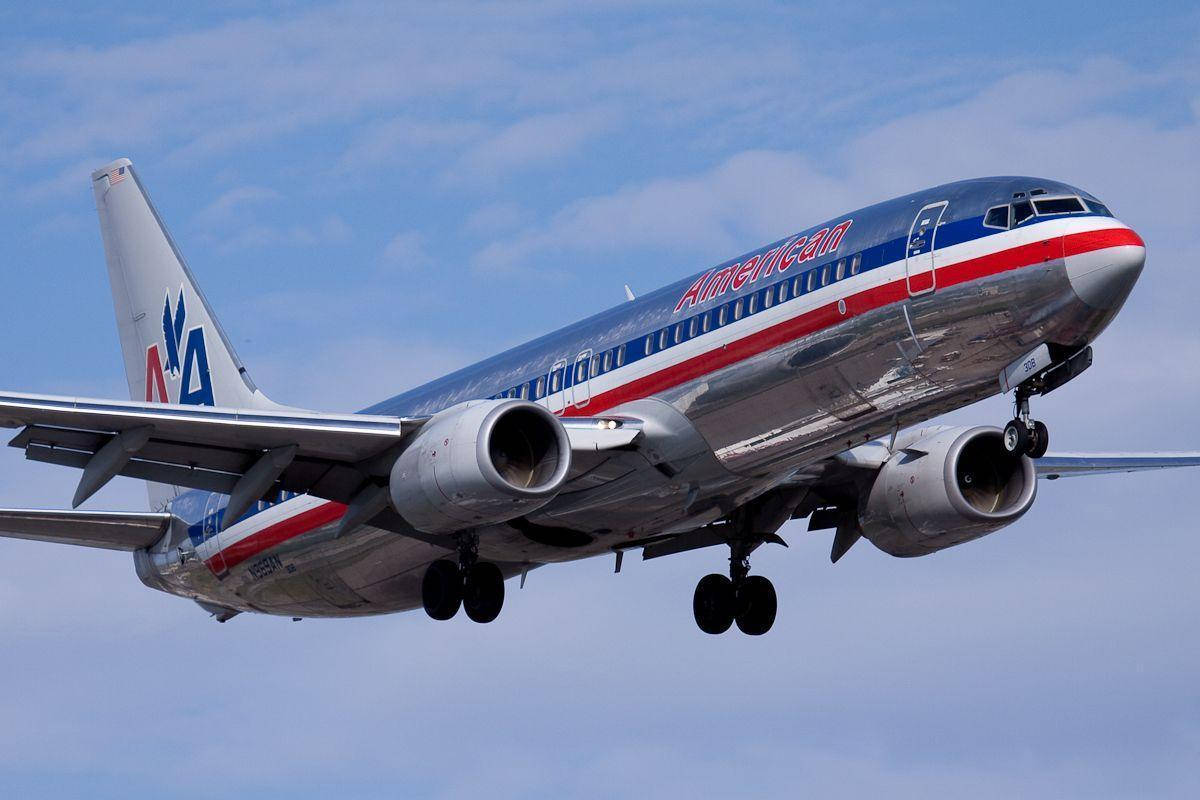 Airlines 桌布 壁紙 — 一架美國航空波音737正在降落，起落架放下，背景是局部多雲的藍天。