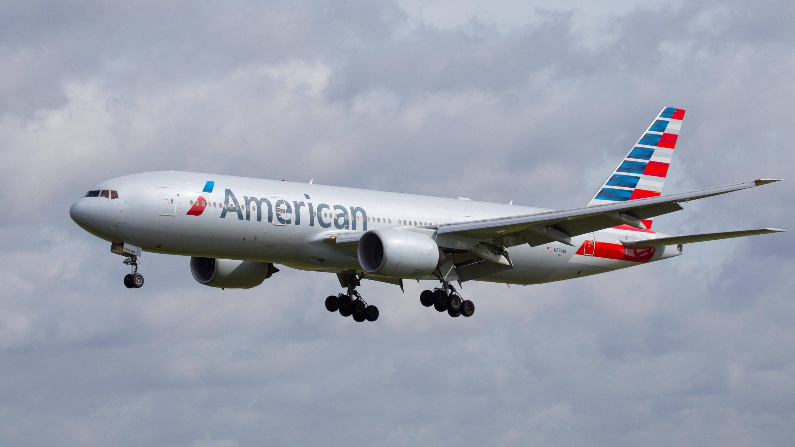 Airlines 桌布 壁紙 — 一架美國航空波音777在多雲的天空下，放下起落架正在降落。