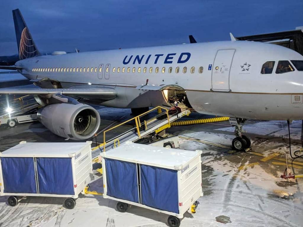 Airport 桌布 壁紙 — 一架聯合航空噴射機在黃昏時停在積雪的停機坪上，附近有登機梯和行李車。