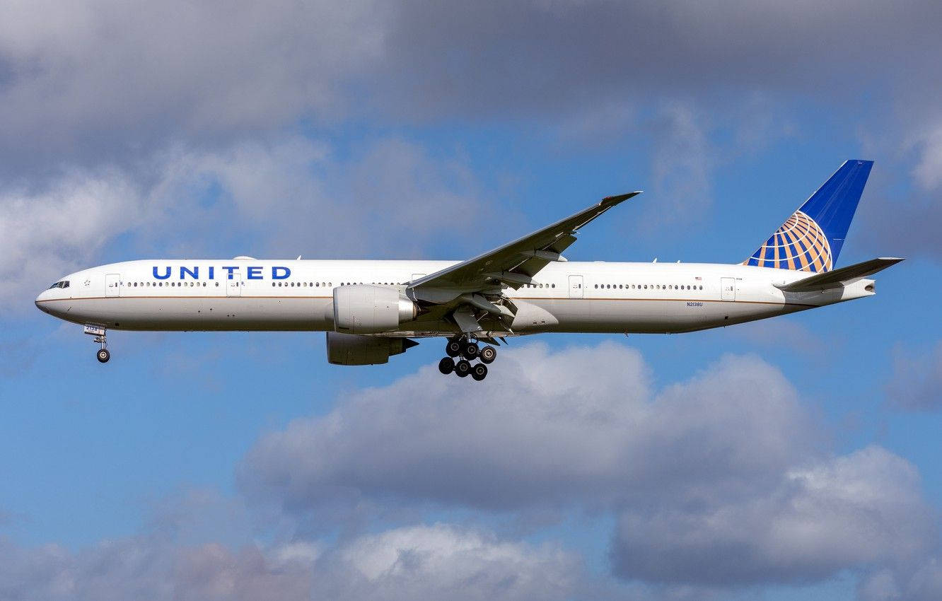 Plane 桌布 壁紙 — 一架聯合航空波音777正在部分多雲的藍天中下降，起落架已放下。