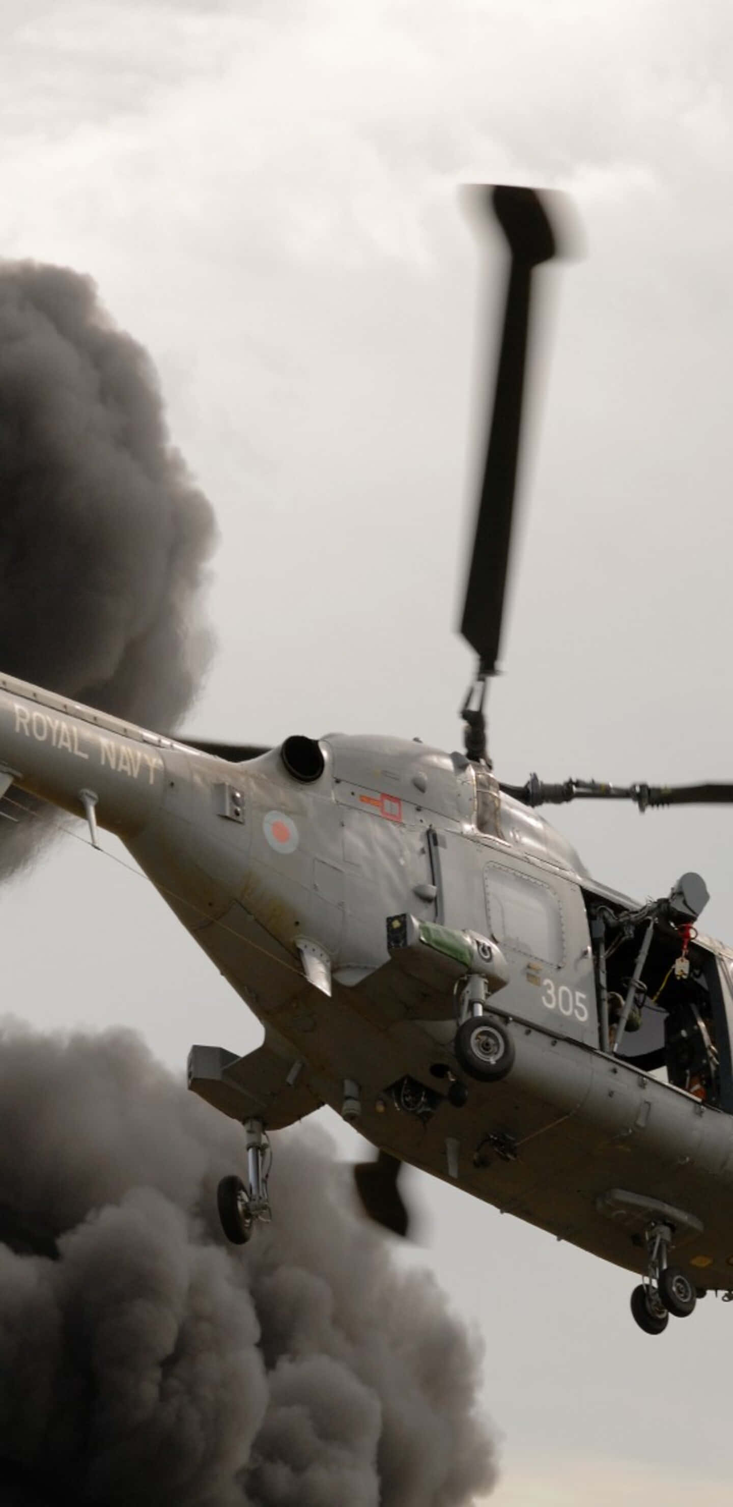Helicopter 桌布 壁紙 — 一架英國皇家海軍直升機在多雲的天空下低飛穿過濃厚的黑煙。