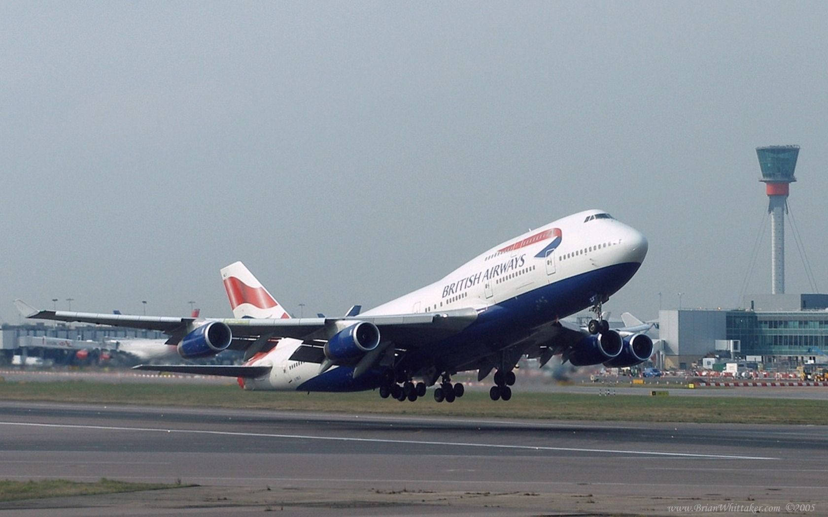 Plane 桌布 壁紙 — 一架英國航空波音747在陰天背景下從跑道起飛，背景有機場建築物和管制塔。