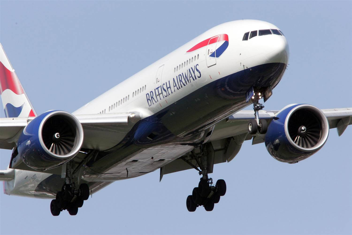 飛機 桌布 壁紙 — 一架英國航空波音777飛機在晴朗的藍天下放下起落架下降。