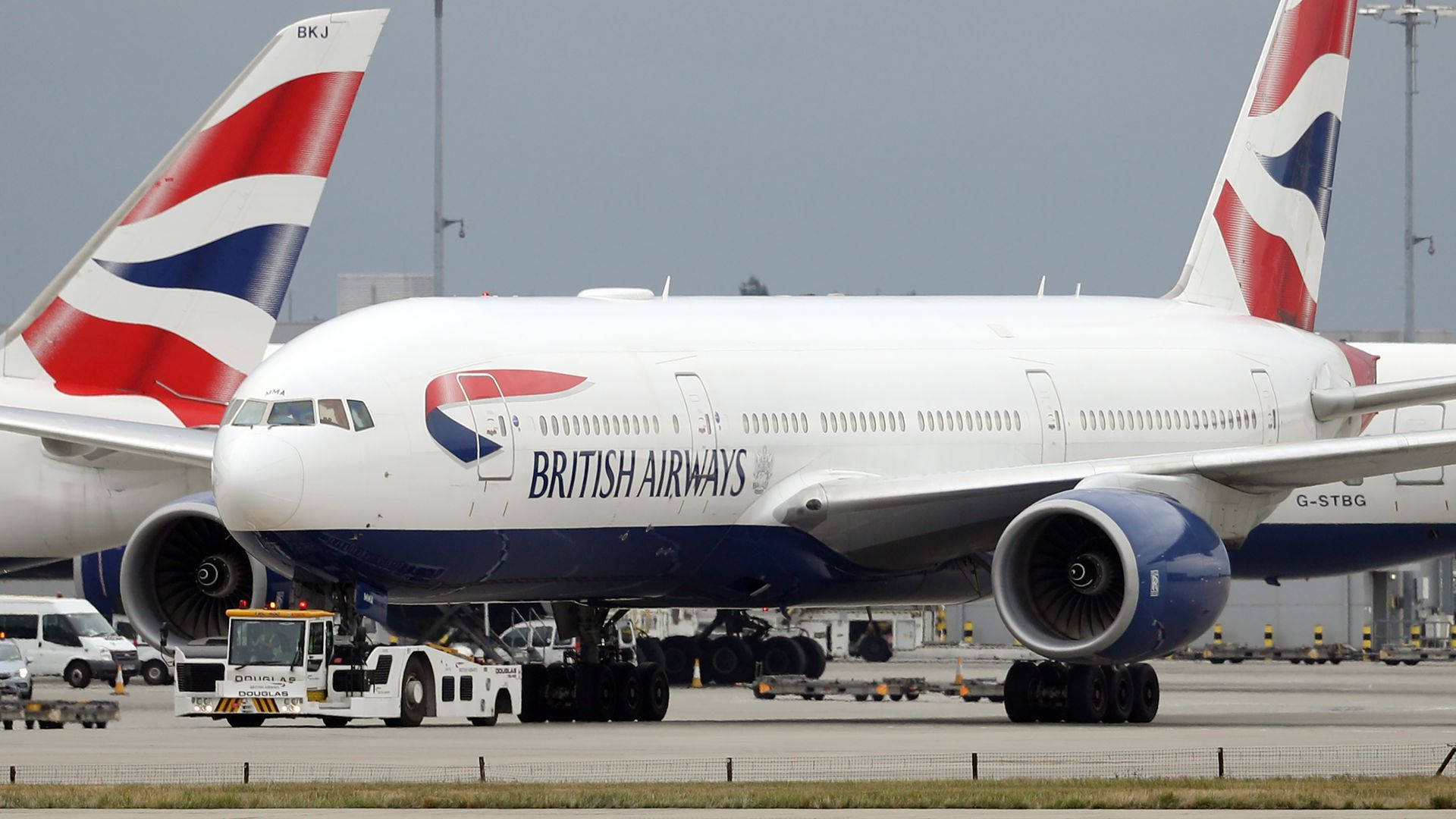 Airport 桌布 壁紙 — 一架英國航空的空中巴士A380停泊在機場閘口，附近有地勤人員和車輛，天空多雲。