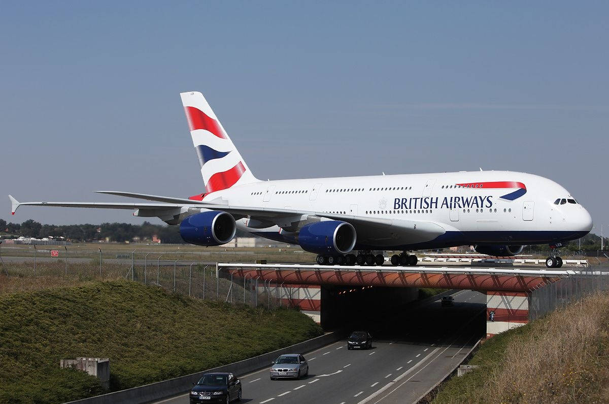  壁紙 — 一架英國航空空中巴士A380飛機在高速公路上方的跑道上滑行，下方有汽車經過。