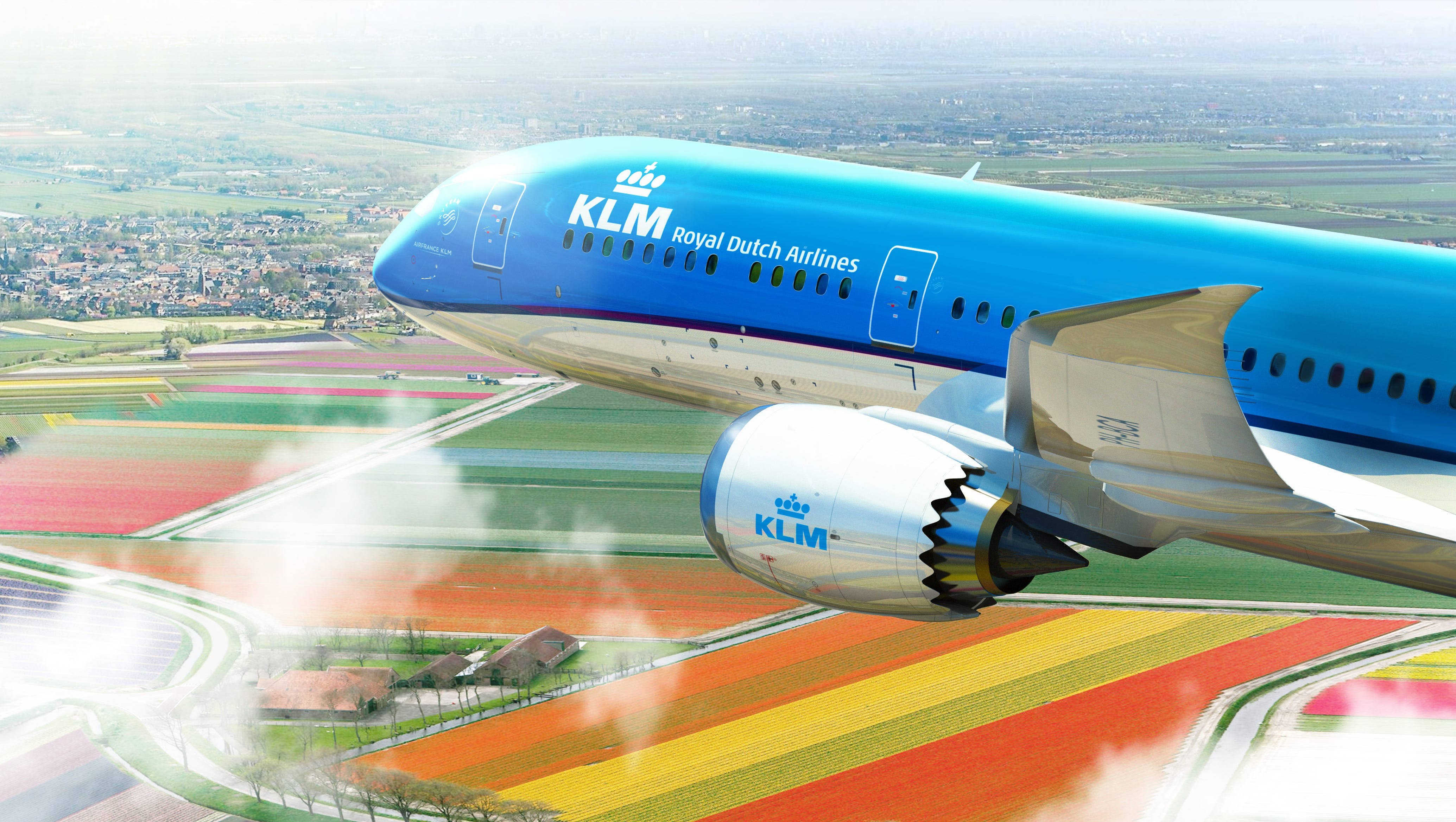 flying 桌布 壁紙 — 一架荷蘭皇家航空 KLM 客機在明亮的日光下，翱翔於色彩斑斕的鬱金香花田之上。