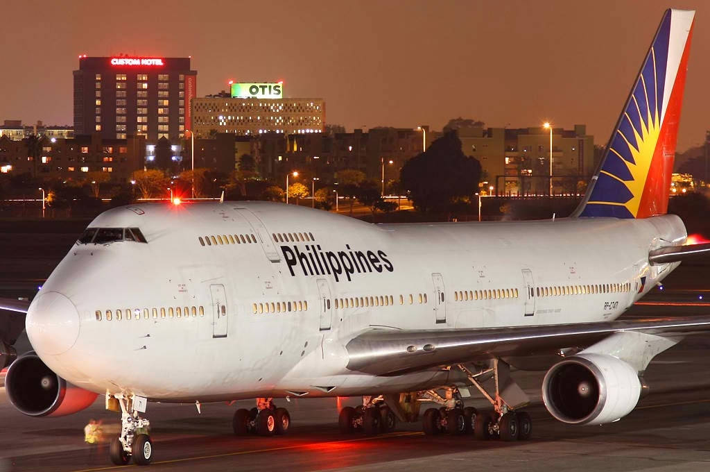 Airport 桌布 壁紙 — 一架菲律賓航空波音747在夜間停泊在機場停機坪，背景中城市燈光閃爍。