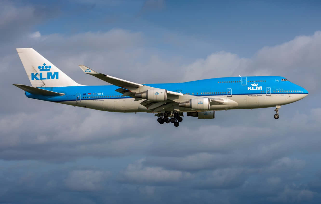 747 Airplane 桌布 壁紙 — 一架藍白塗裝的KLM波音747正在放下起落架，穿過多雲的天空下降。