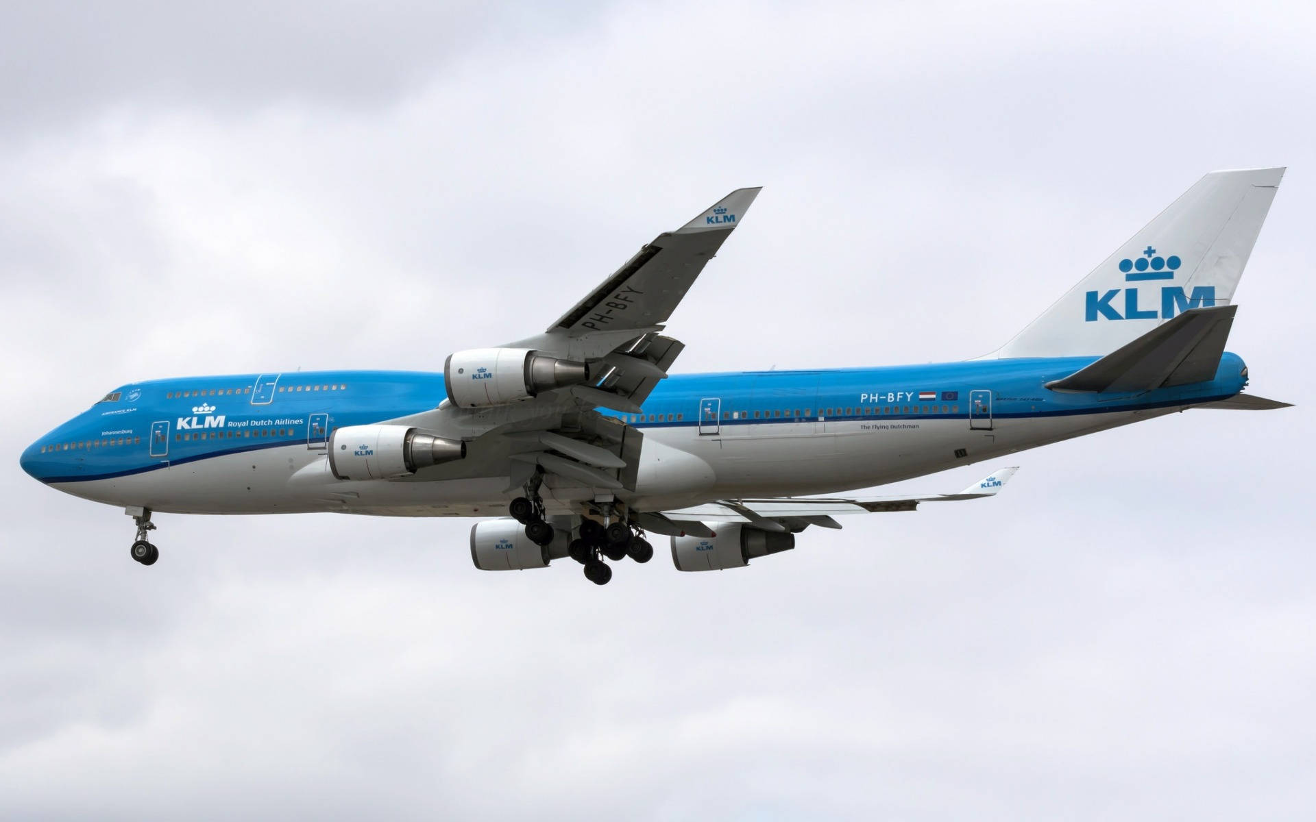 飛機 桌布 壁紙 — 一架藍白塗裝的KLM波音747正在放下起落架，在陰雲密佈的天空中下降。