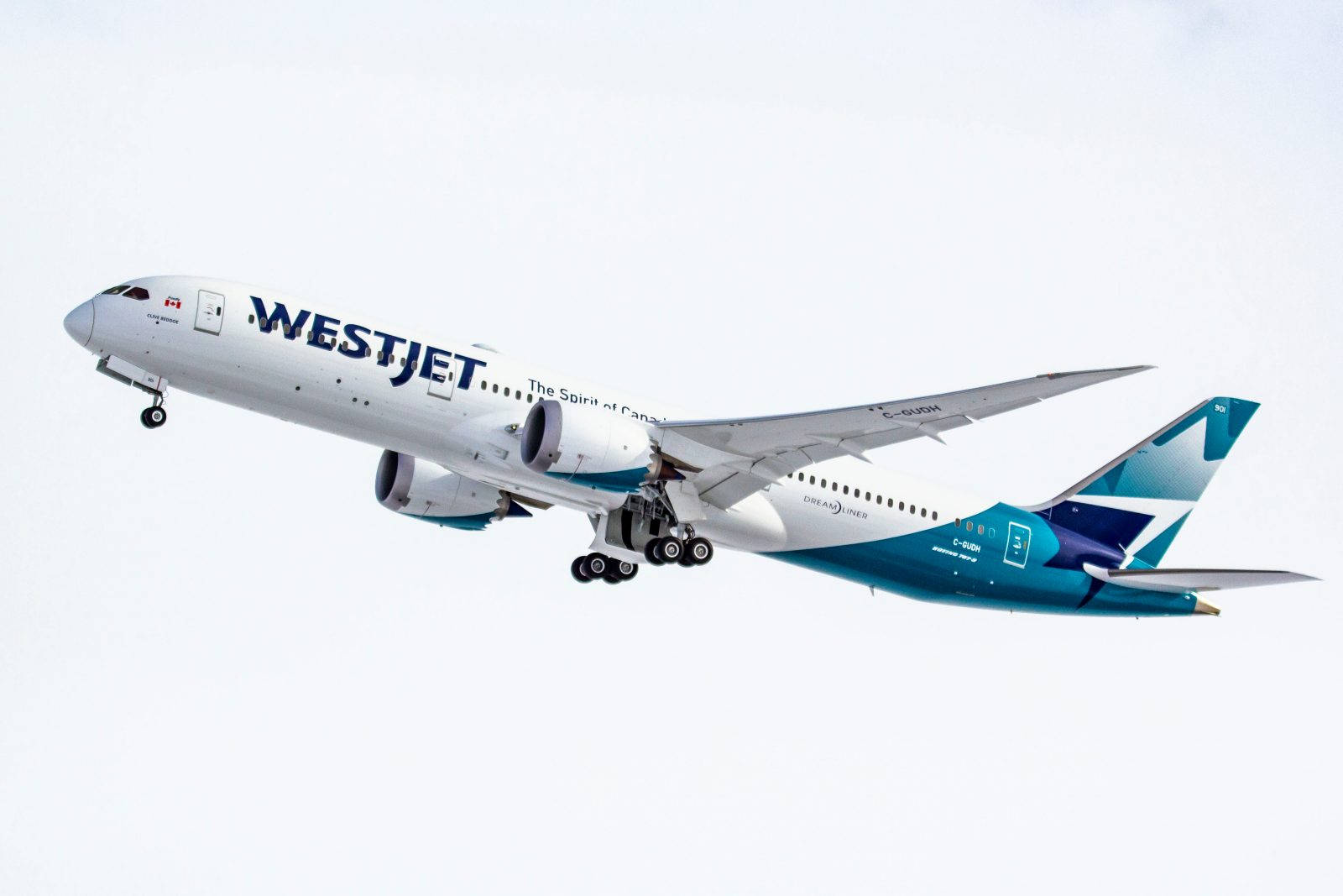 Plane 桌布 壁紙 — 一架藍白塗裝的西捷航空波音787夢想客機在日間飛行中優雅地傾斜，背景是淡色的天空。