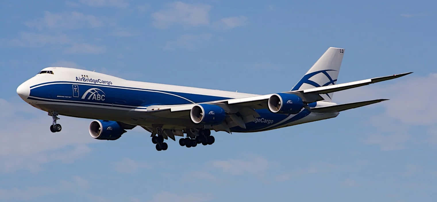 Jumbo Jets 桌布 壁紙 — 一架藍白相間的AirBridgeCargo波音747貨機在晴朗的藍天中翱翔，起落架放下。