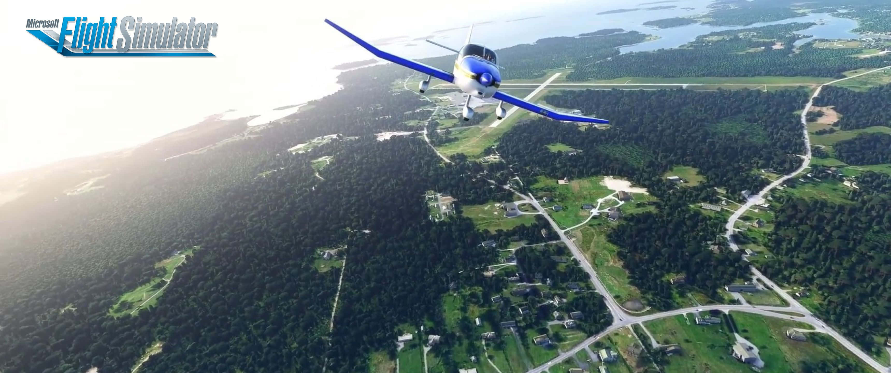 3440x1440p Microsoft Flight Simulator 桌布 壁紙 — 一架藍白相間的單引擎飛機在明亮的日光下低飛過一個有湖泊、道路和房屋的森林景觀。