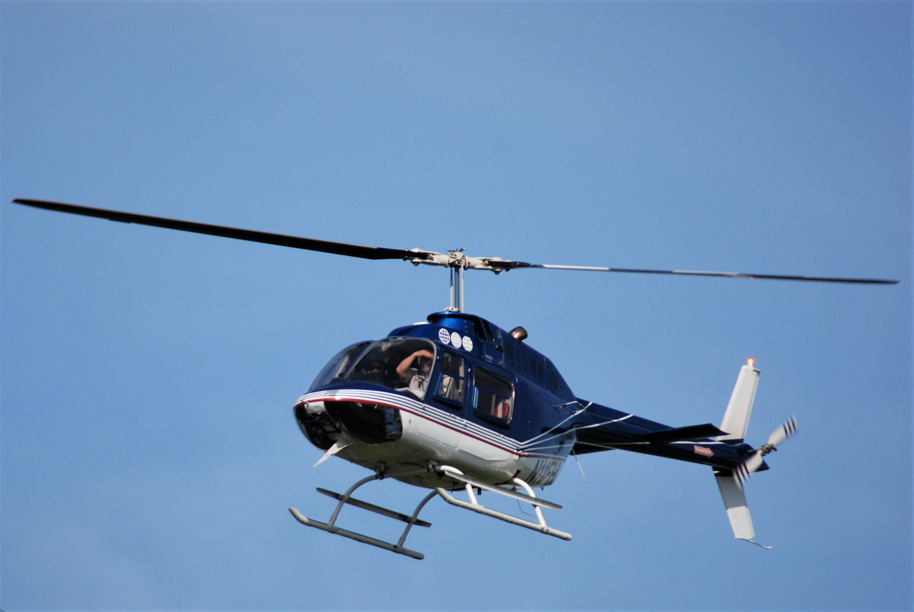 Helicopter 桌布 壁紙 — 一架藍白相間的直升機在晴朗的藍天中翱翔，旋翼轉動。