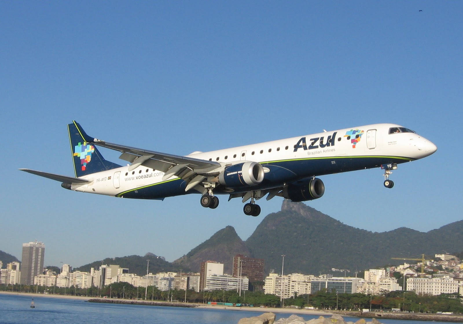 飛機 桌布 壁紙 — 一架藍色巴西航空（Azul Airlines）飛機在清澈的藍天下下降，下方是里約熱內盧的標誌性山脈和城市景觀。