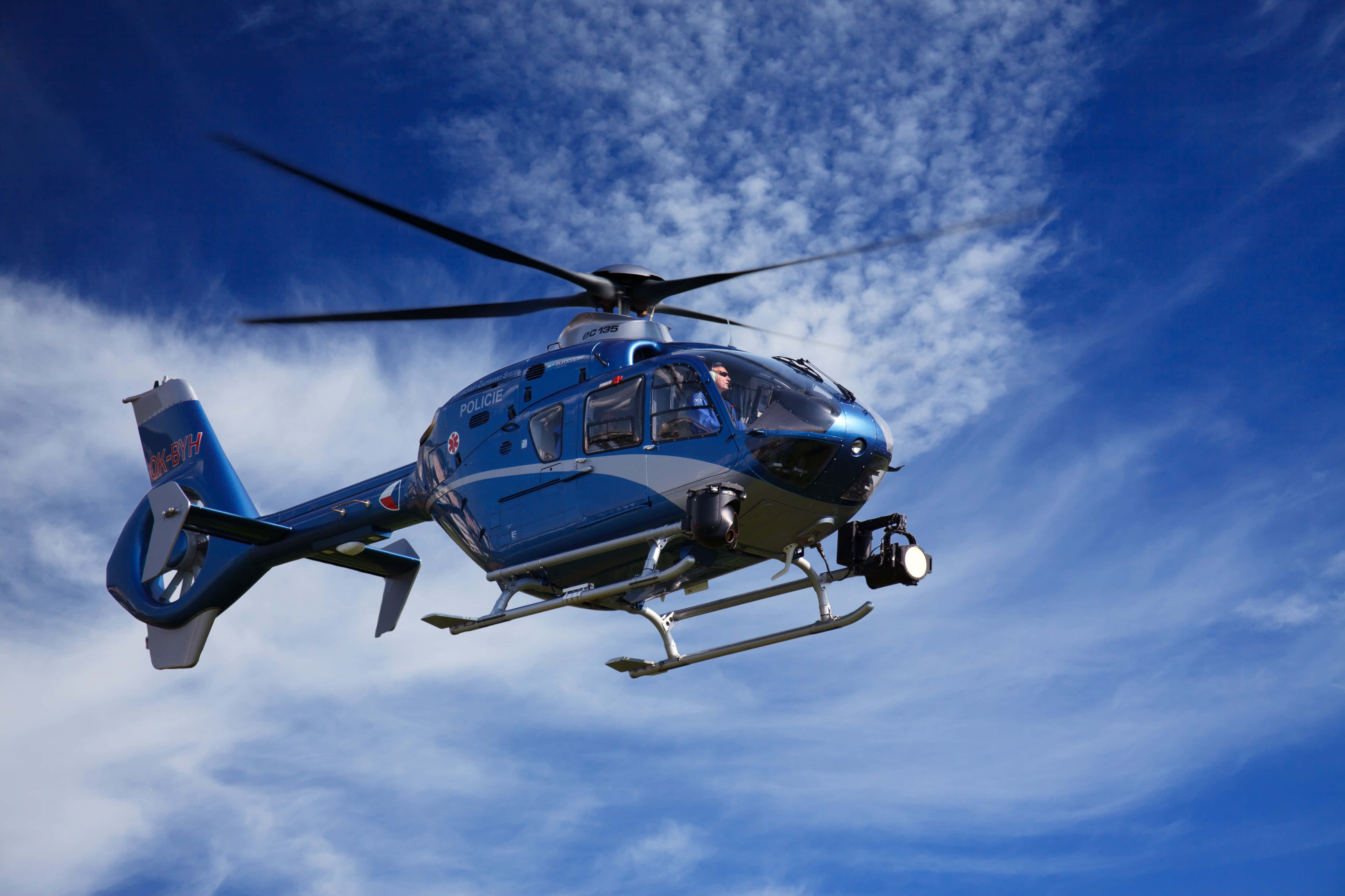 Helicopter 桌布 壁紙 — 一架藍色警用直升機在明亮的藍天中翱翔，伴隨著縷縷白雲。