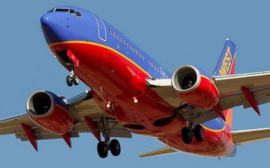 Southwest Airlines 桌布 壁紙 — 一架西南航空的噴射客機，以鮮豔的紅藍塗裝，在晴朗的藍天下放下起落架下降。