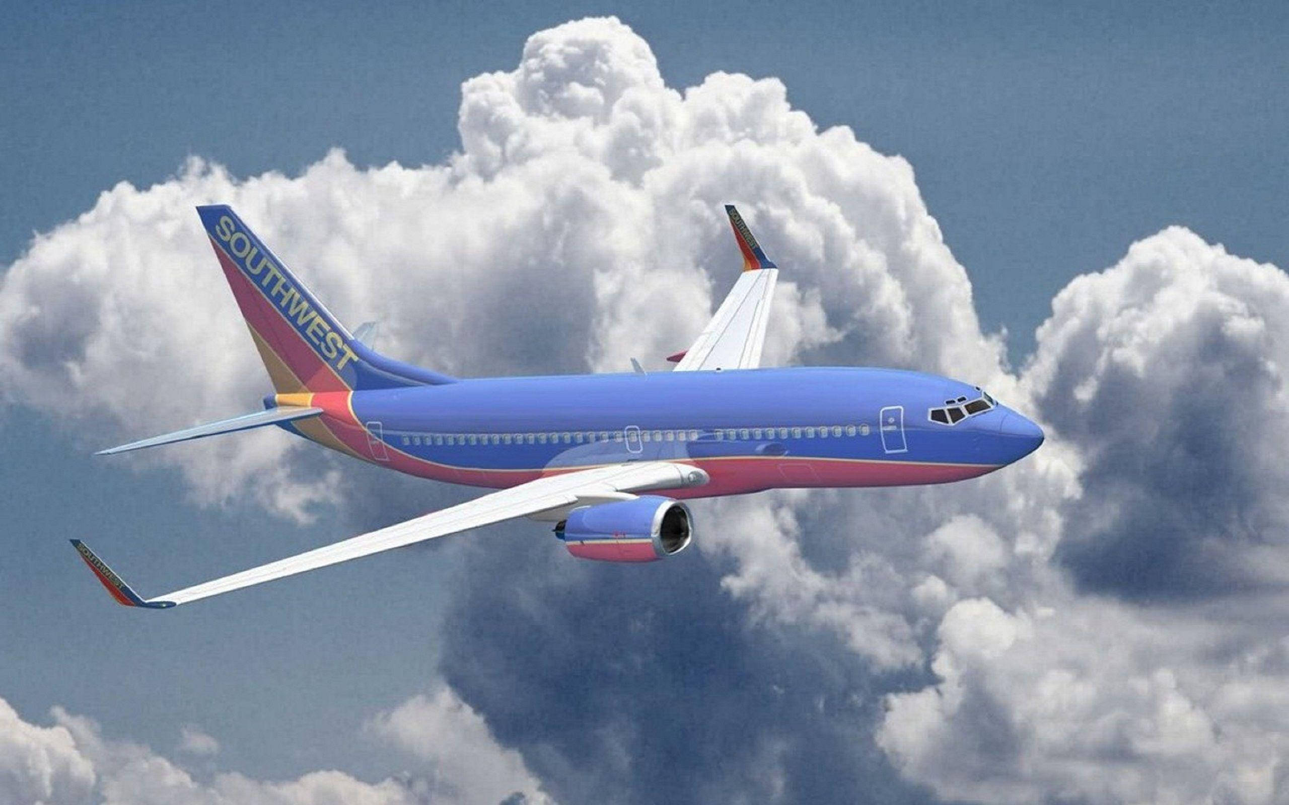 Plane 桌布 壁紙 — 一架西南航空的飛機在晴朗的藍天中穿過蓬鬆的白雲翱翔。