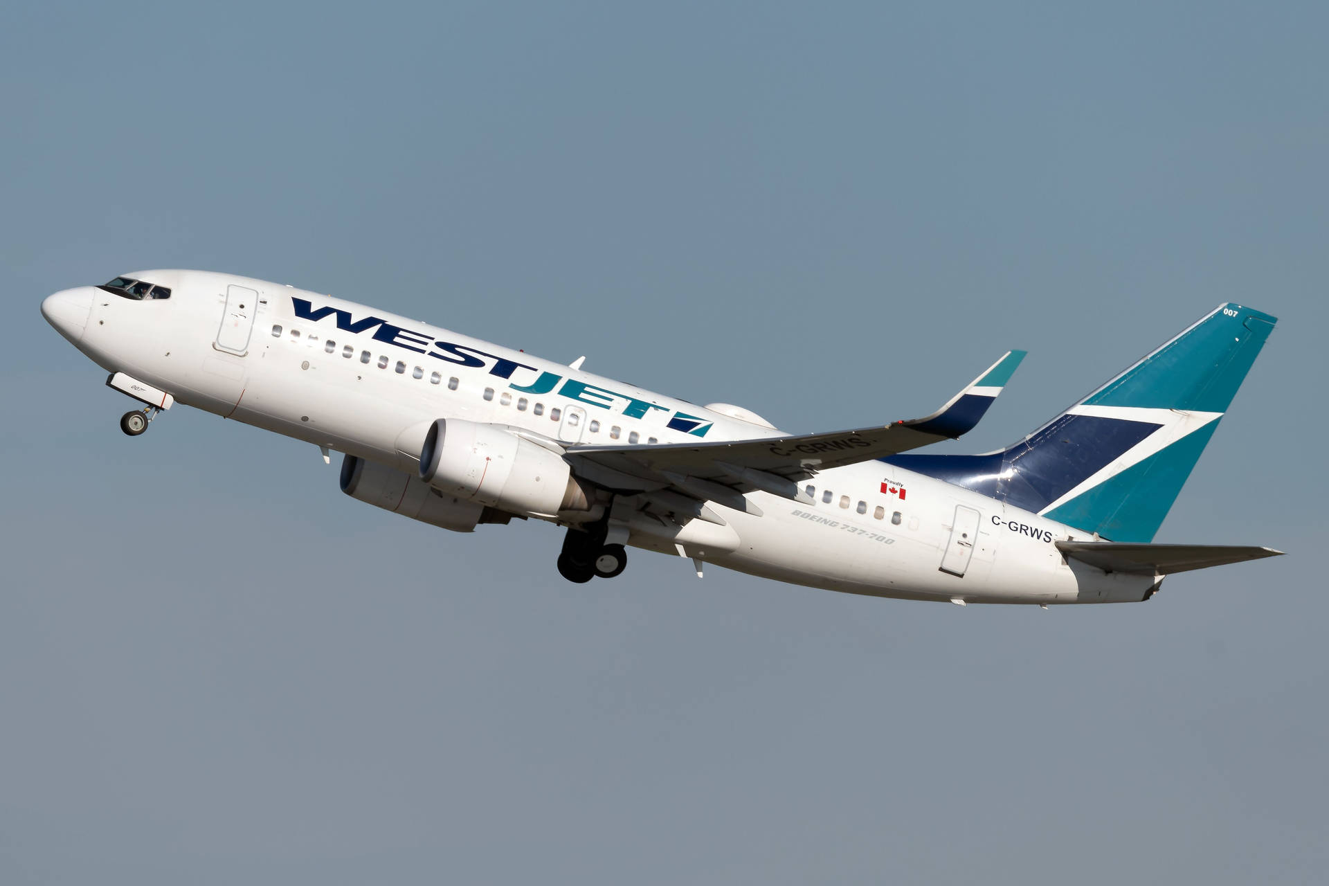  壁紙 — 一架西捷航空波音737客機正在飛行，起落架放下，背景是晴朗的藍天。