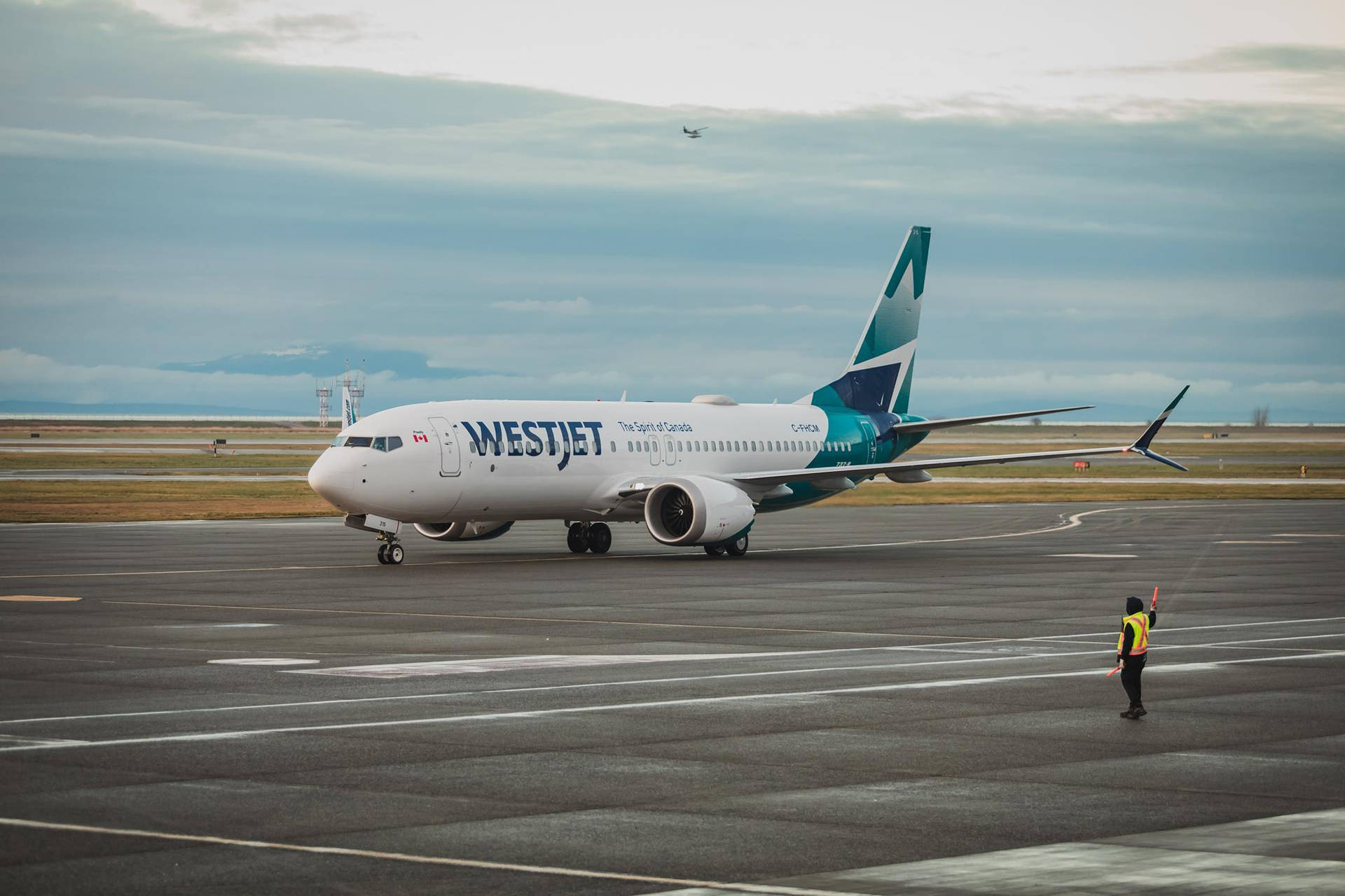  壁紙 — 一架西捷航空飛機在多雲的機場停機坪滑行，地勤人員用手勢指揮交通。