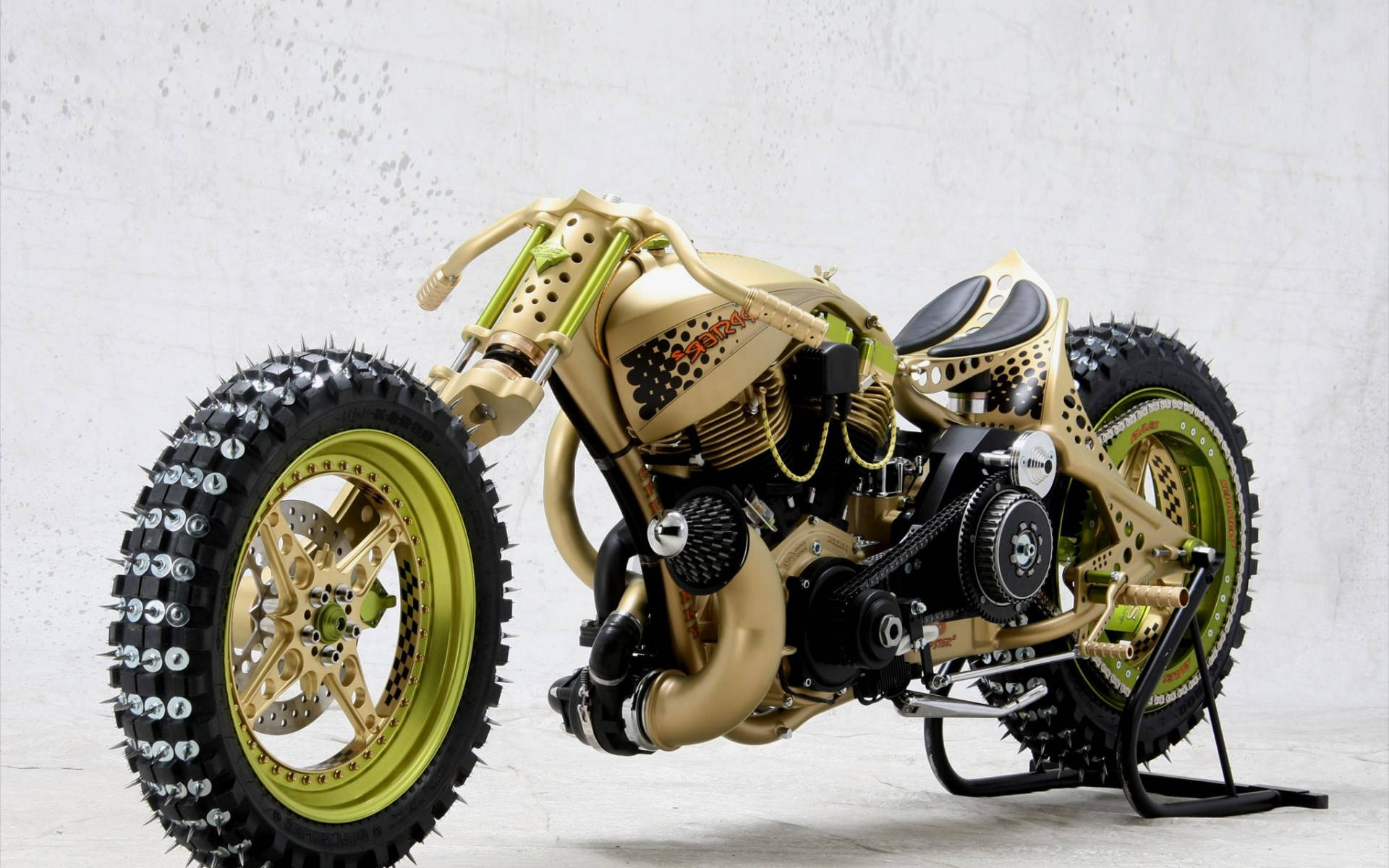 Cool Bike 桌布 壁紙 — 一架訂製的金色和萊姆綠色chopper機車，配備釘胎和暴露的機械細節，靠著一面有紋理的白色牆壁。