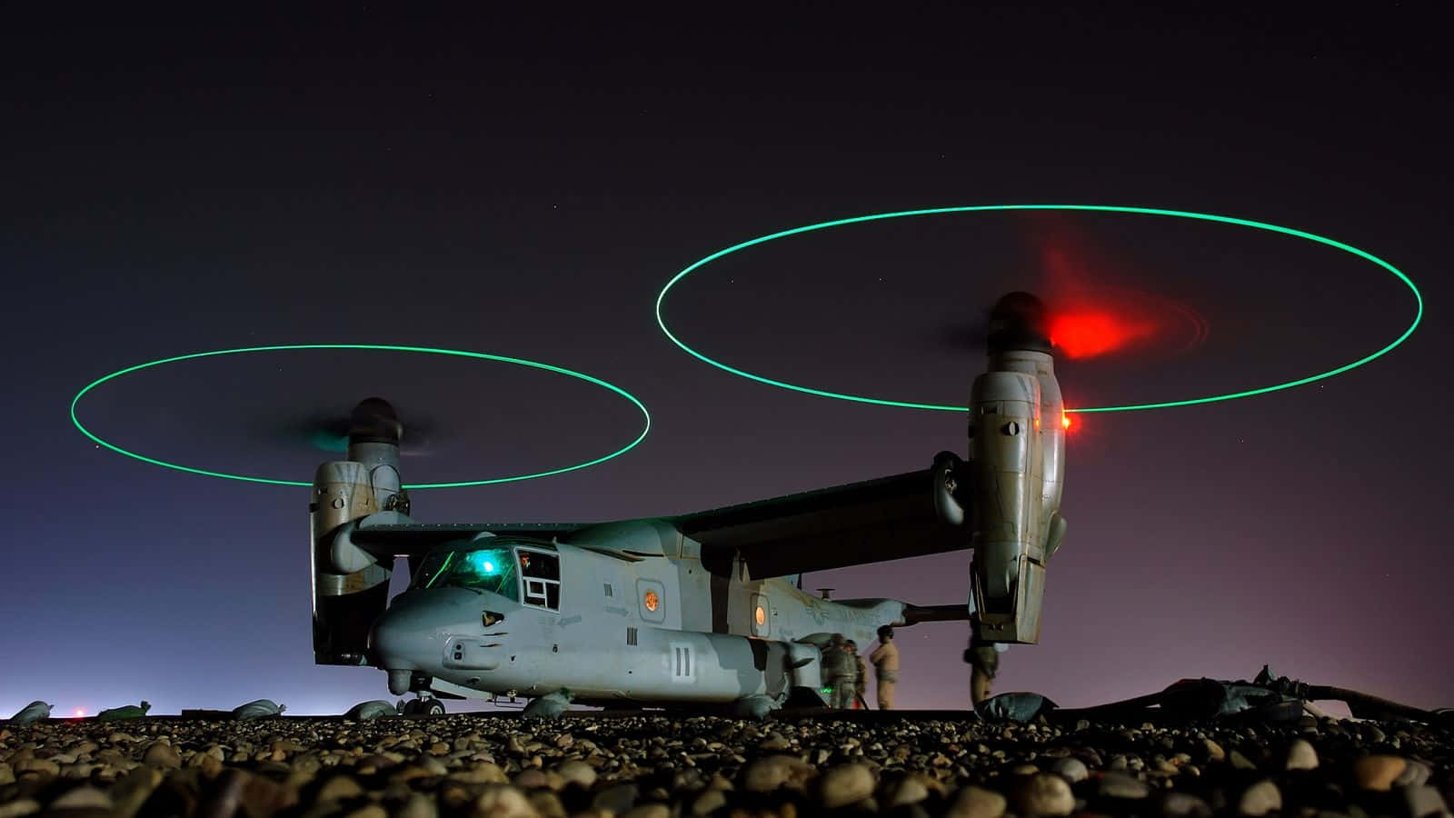 Aircraft 桌布 壁紙 — 一架軍用傾轉旋翼機在夜間懸停，帶有發光的綠色旋翼軌跡和紅色燈光，背景是星空。